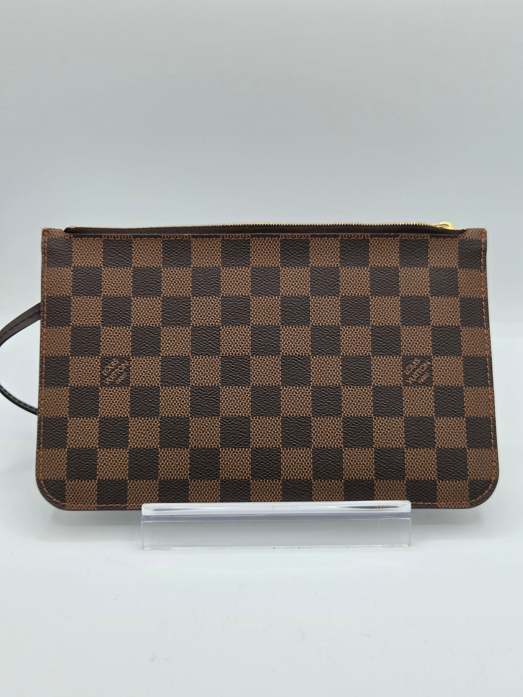 A brown and dark brown checkered zip-around notebook or planner cover with a small white card partially inserted on the right side, photographed against a plain light background.