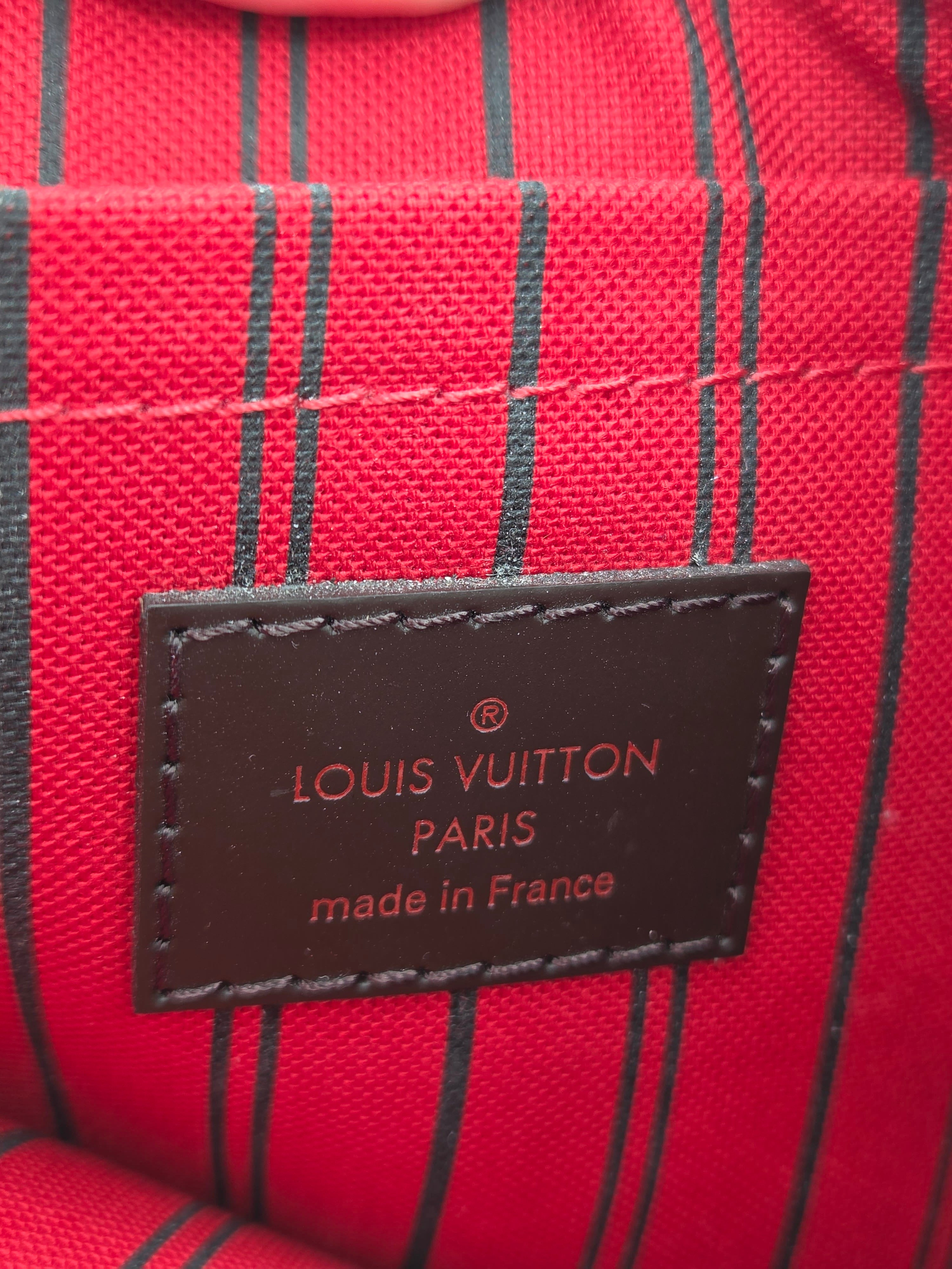 Close-up of a Louis Vuitton patch on red and black striped fabric, with the text 'LOUIS VUITTON PARIS made in France' visible.