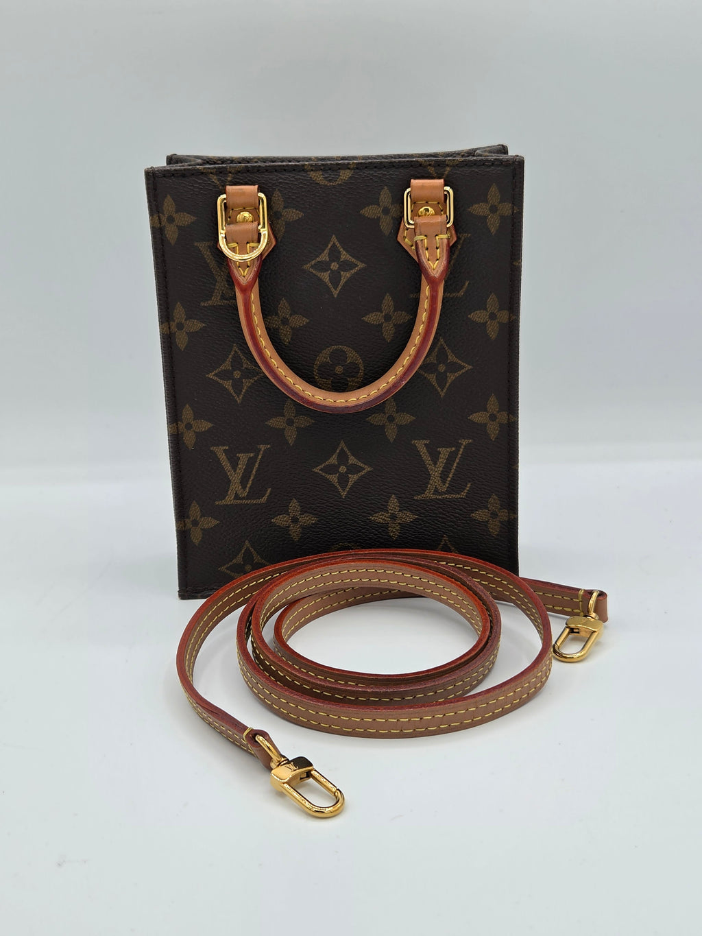 Louis Vuitton monogram canvas shoulder bag with brown leather strap and gold-tone hardware, photographed on a plain light background.