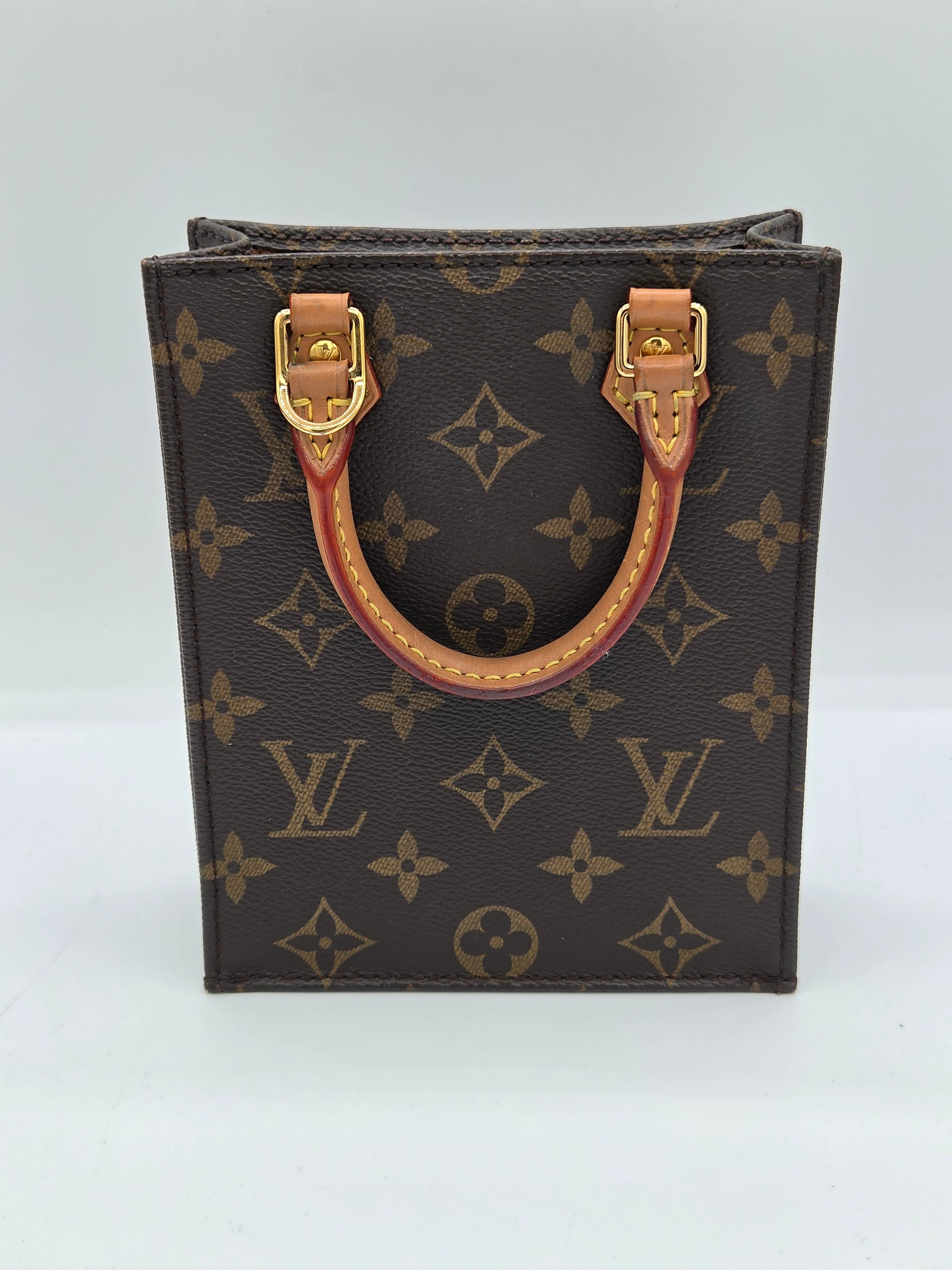 A Louis Vuitton monogram canvas top-handle pouch or small bag, shown from above on a plain white background. The dark brown coated canvas features the classic tan monogram pattern, with a tan leather handle and gold-tone hardware.