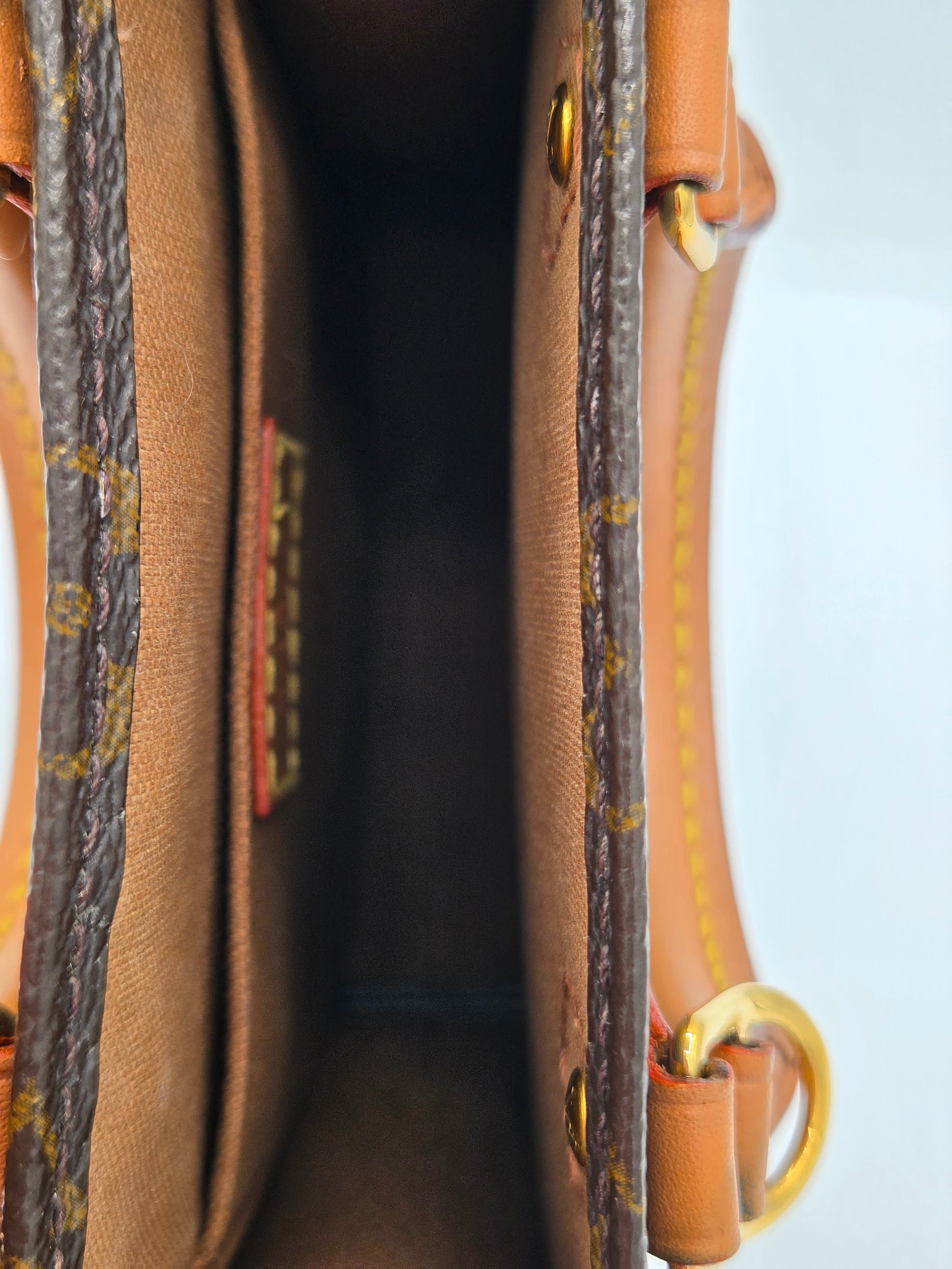 Close-up of the interior of a Louis Vuitton handbag, showing the tan monogram canvas lining, brown leather trim, and gold-tone hardware.