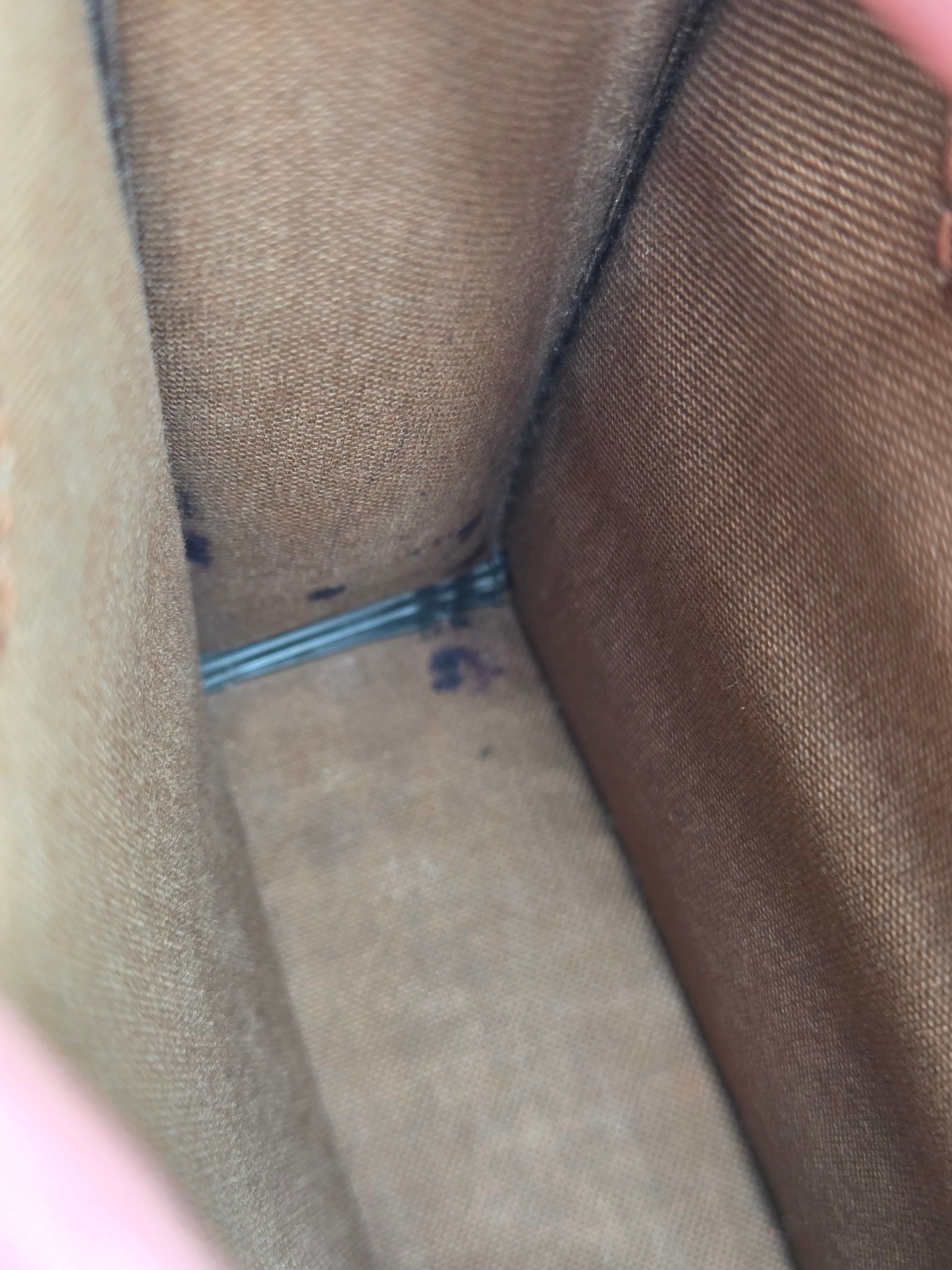 Close-up of the interior corner of a brown canvas or fabric bag, showing the woven texture and a small metal zipper pull.
