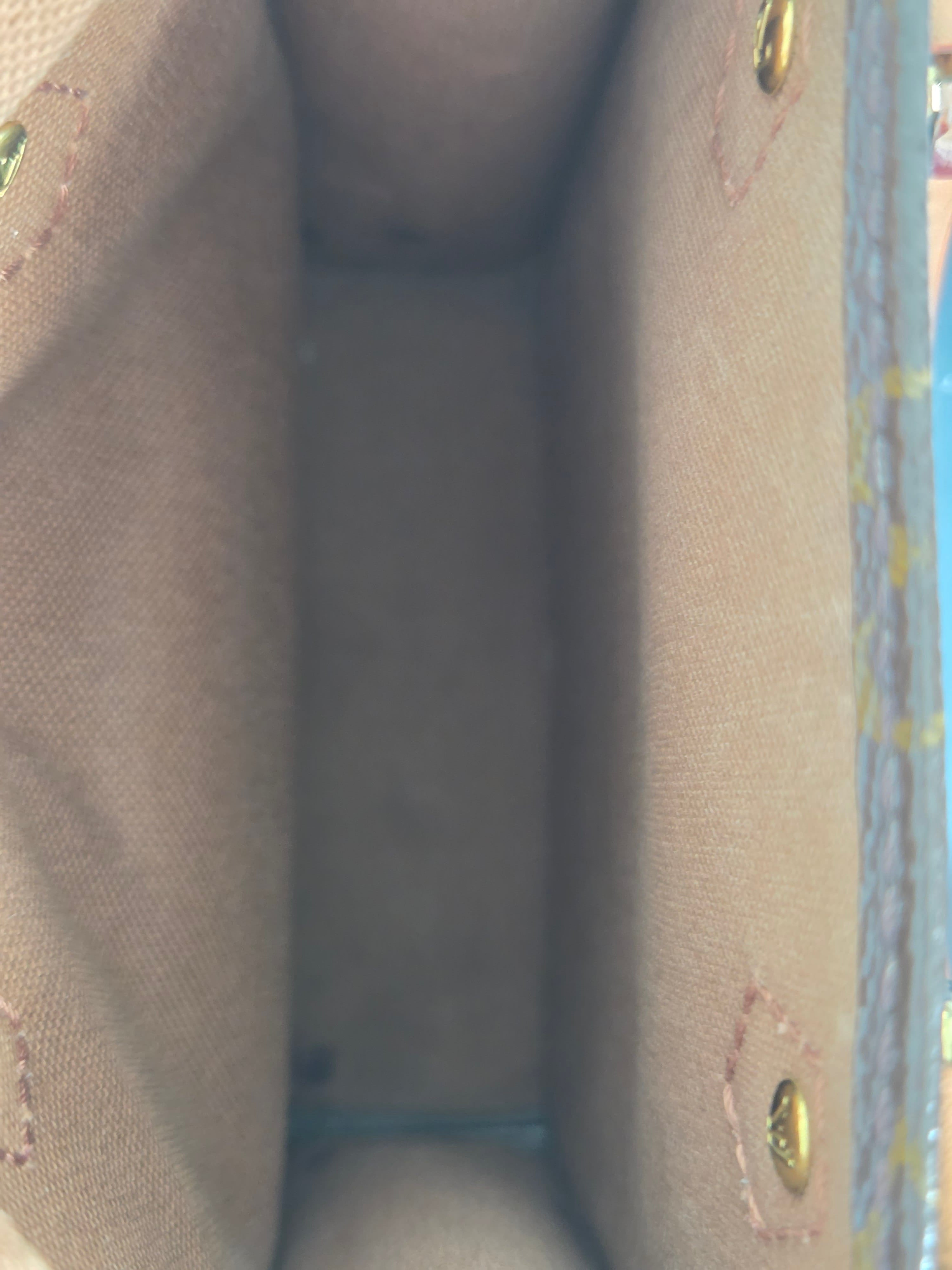 Close-up view of the interior lining of a beige canvas or fabric bag, showing the texture of the material and small brass grommets near the top corners.