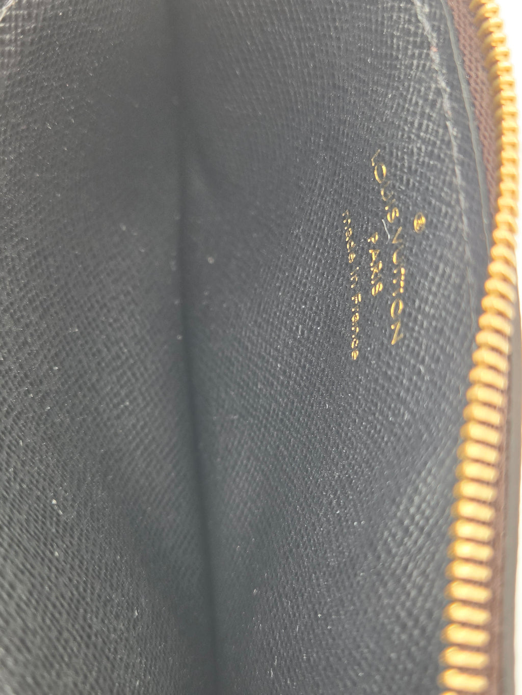Close-up of a Louis Vuitton toiletry bag interior showing the black textured canvas and gold zipper along the top edge.