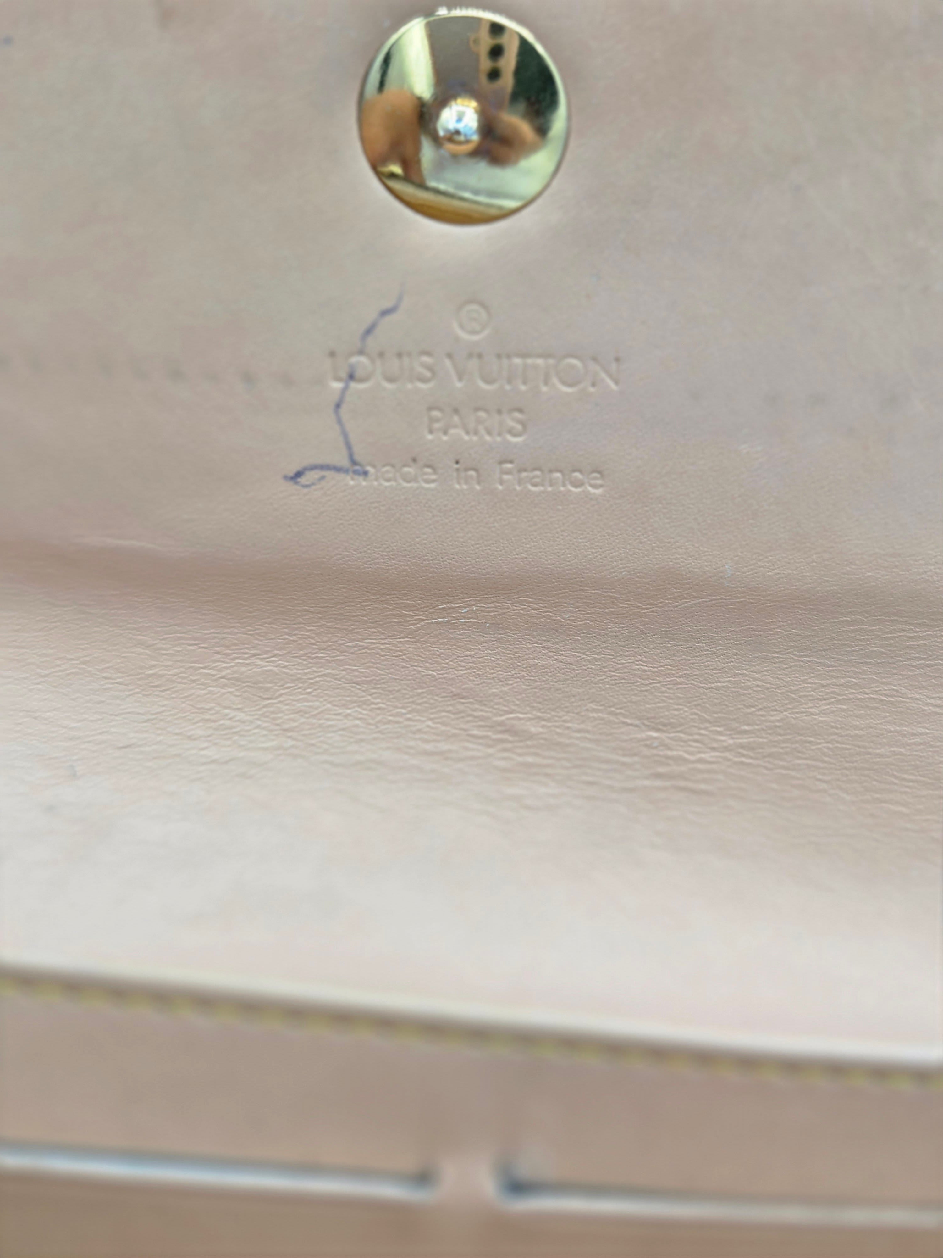Close-up of a light beige leather Louis Vuitton bag showing the 'LOUIS VUITTON MADE IN FRANCE' stamp and a round metal stud closure.