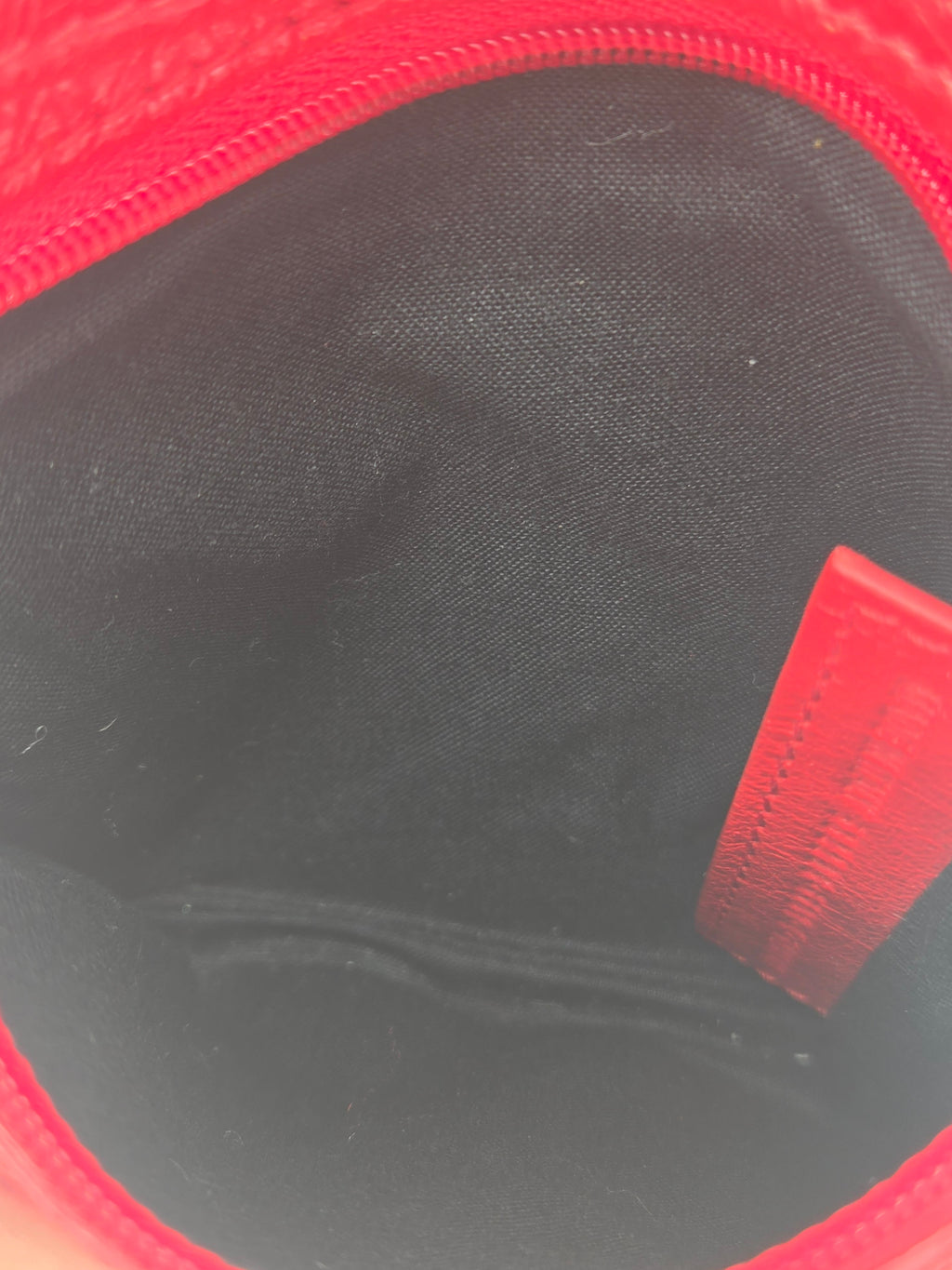 Close-up view of the interior of a red zippered pouch or bag, showing a black fabric lining and a red interior label.