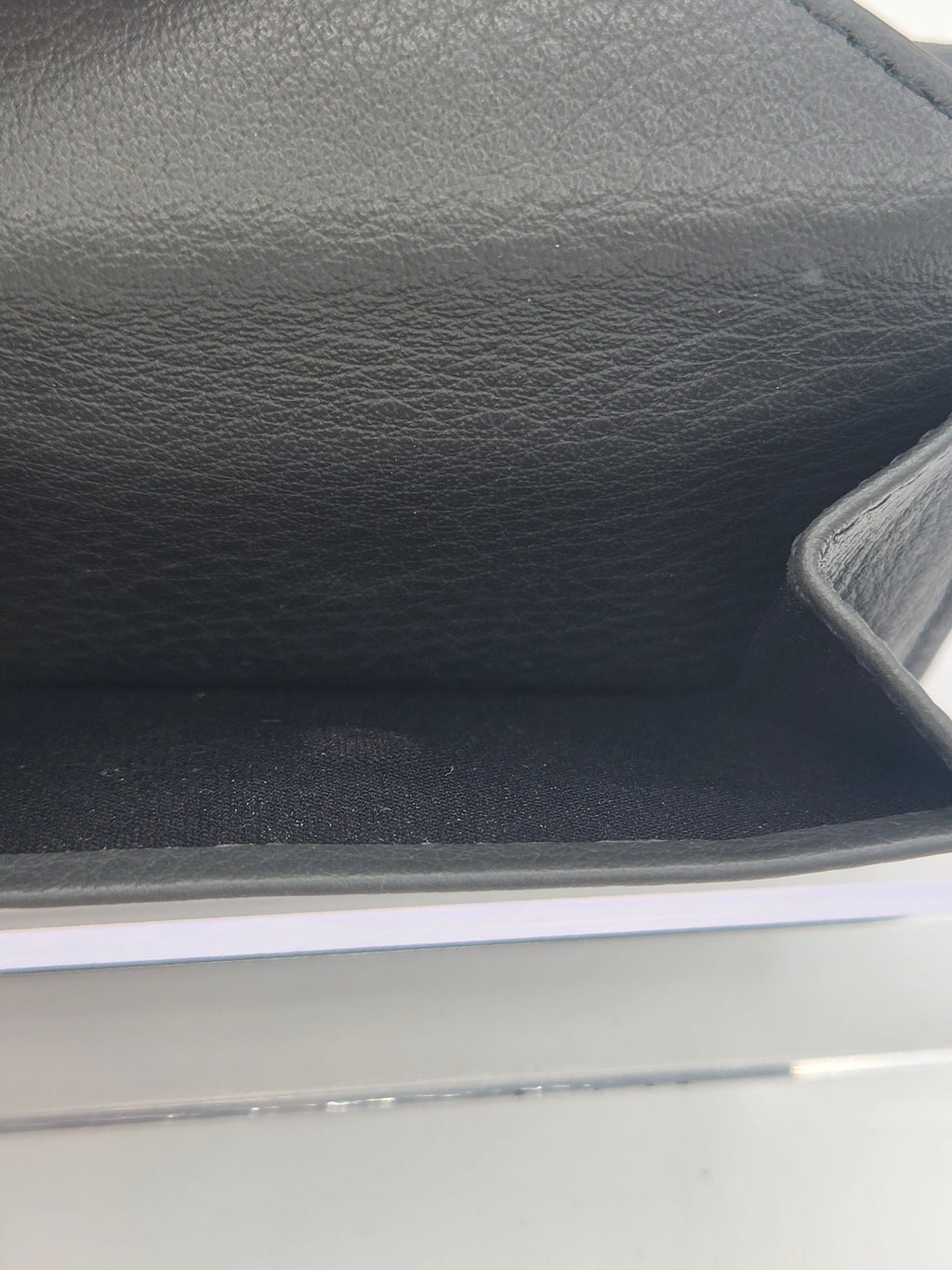 Close-up of a black textured leather or faux-leather item, showing the interior corner and grainy surface texture.