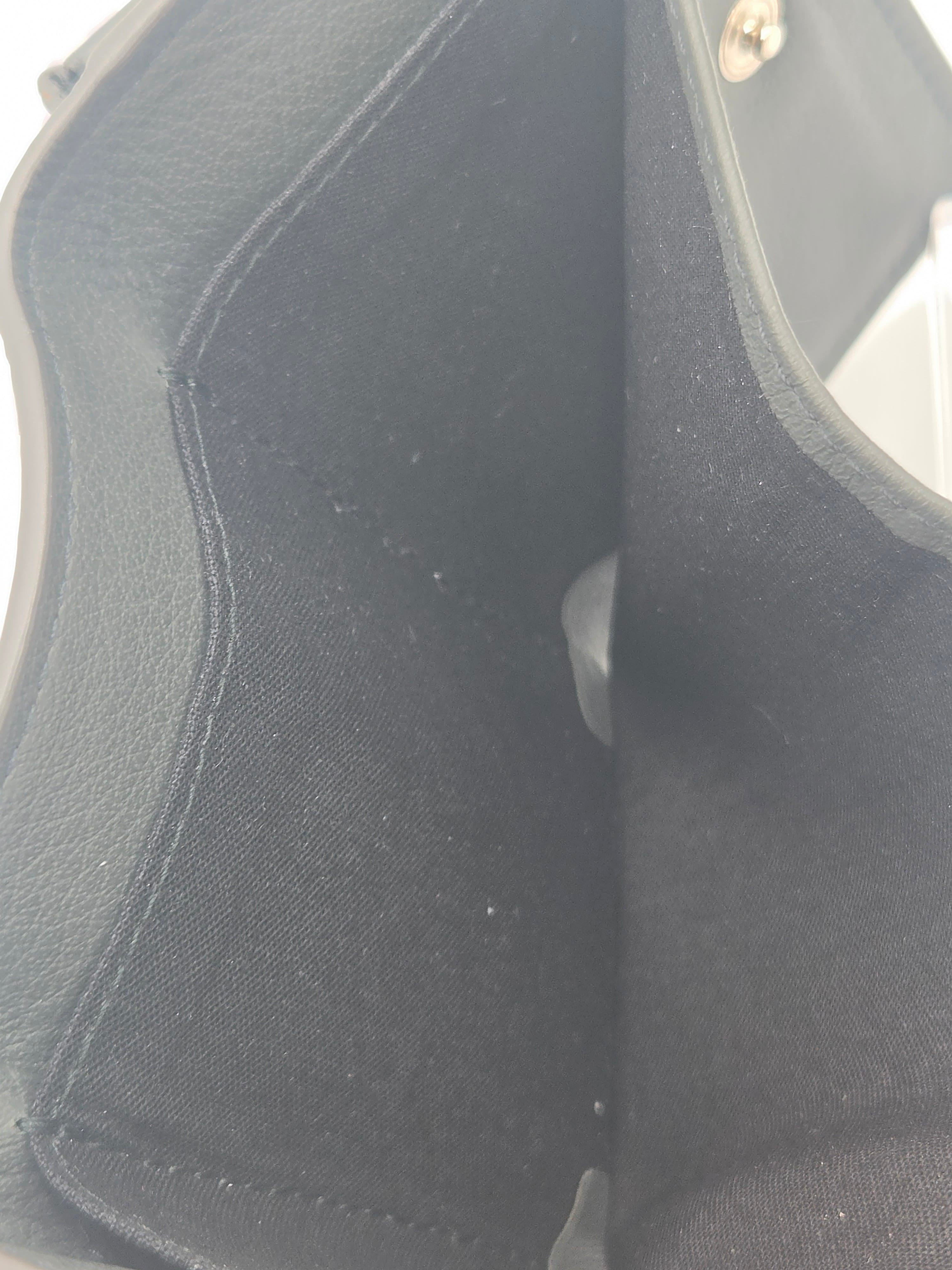 Close-up of a black fabric or faux-leather interior with stitched edges and a small metallic snap visible in the upper left corner.