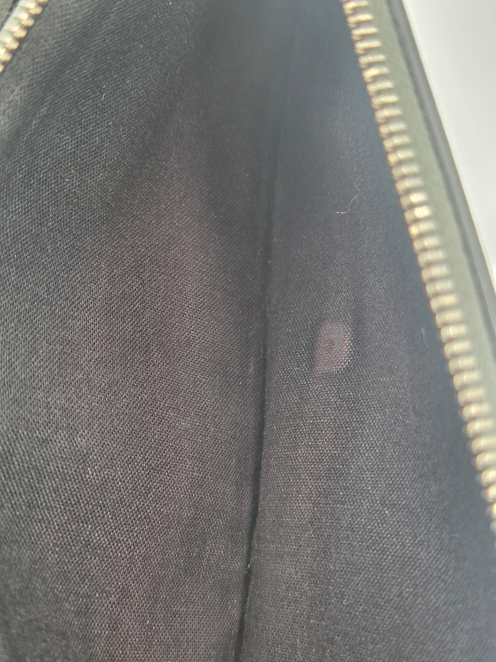 Close-up of a black fabric interior with a gold zipper along the right edge.