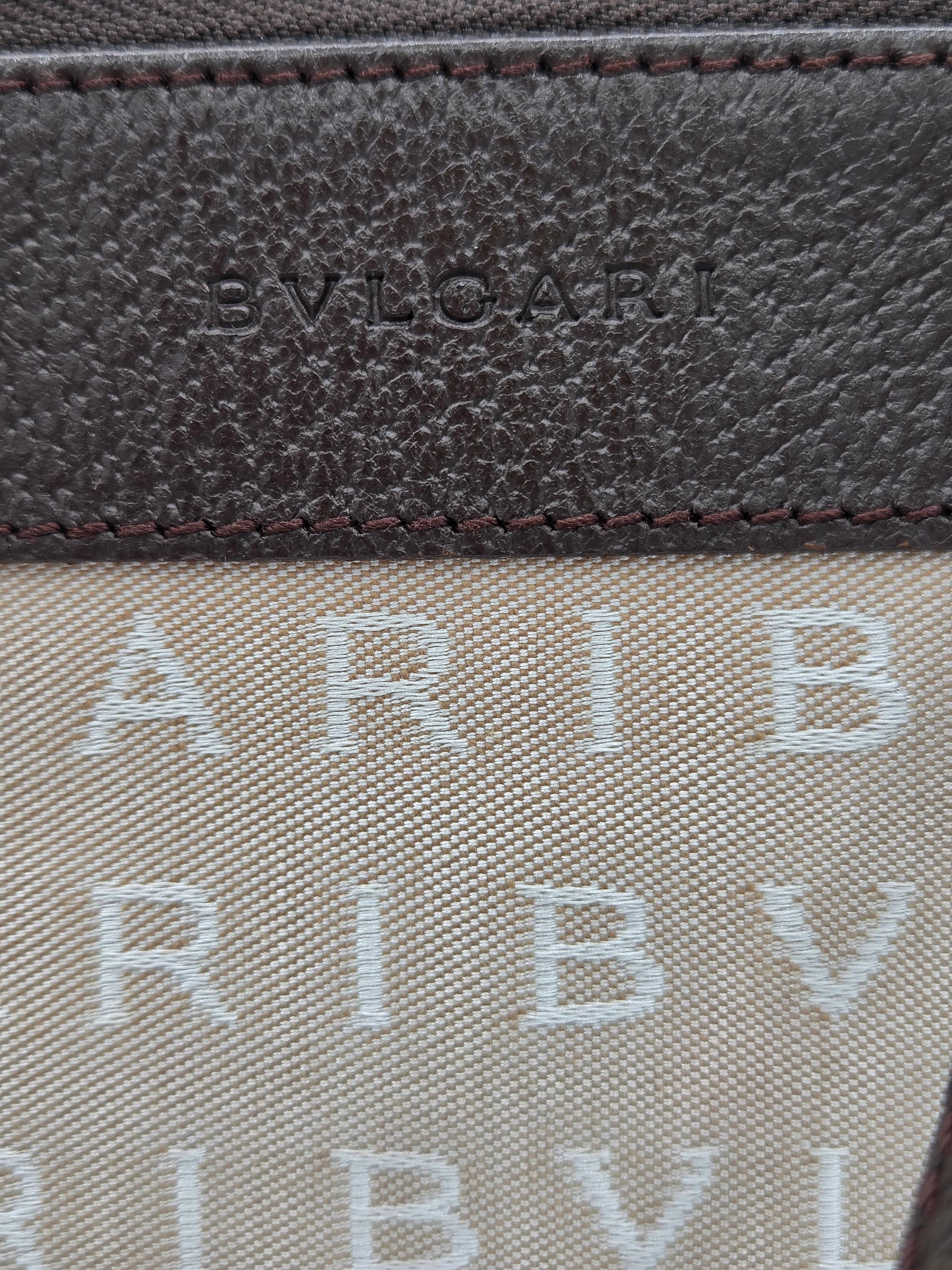 Close-up detail of a luxury wallet or card case featuring a dark brown textured leather panel with debossed 'BVL' branding and a beige canvas section with repeating light gray 'ARIB V.