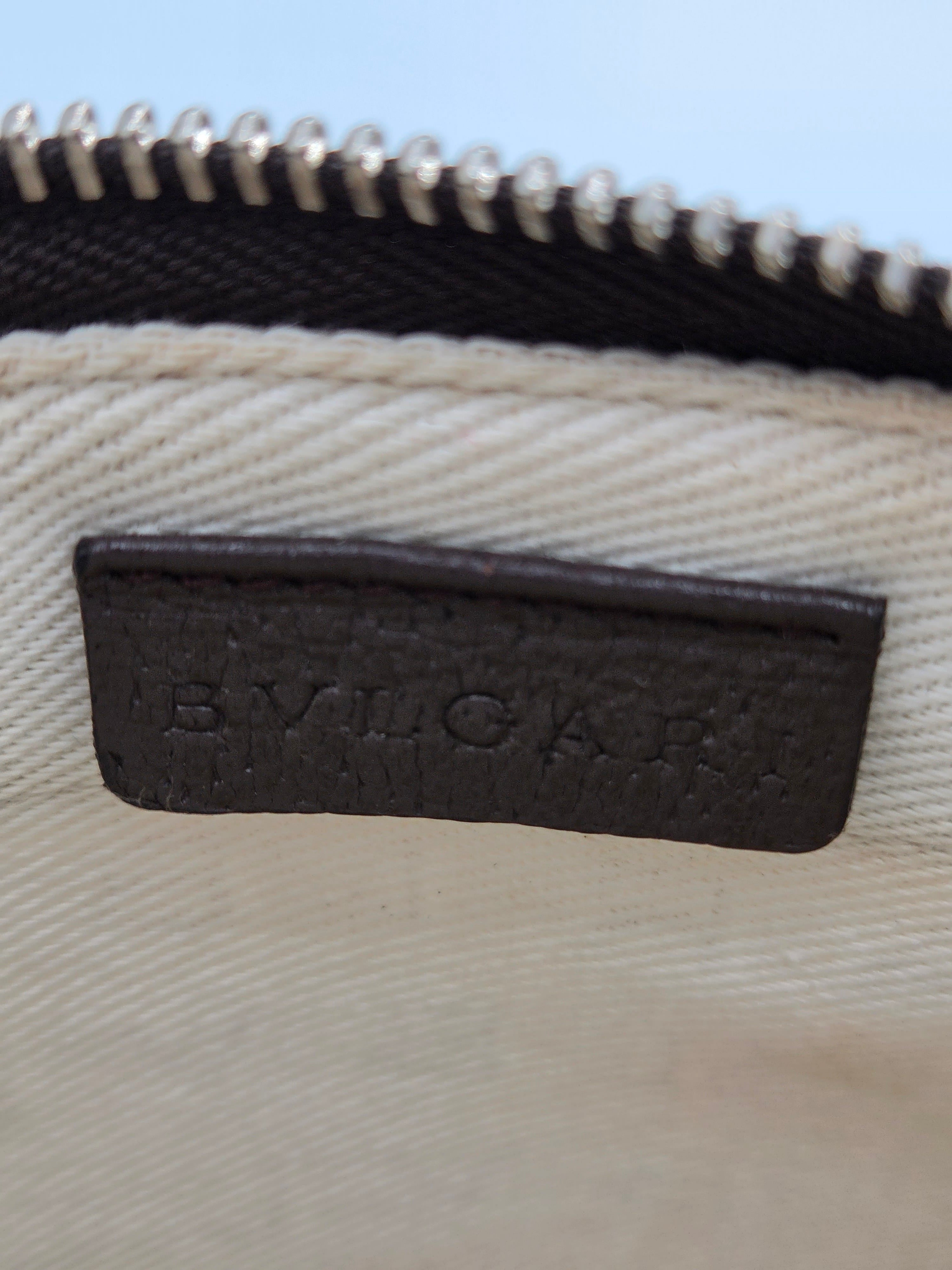 Close-up of a beige canvas bag with a black leather patch embossed with the brand name 'BYUCKAR' next to a black zipper.