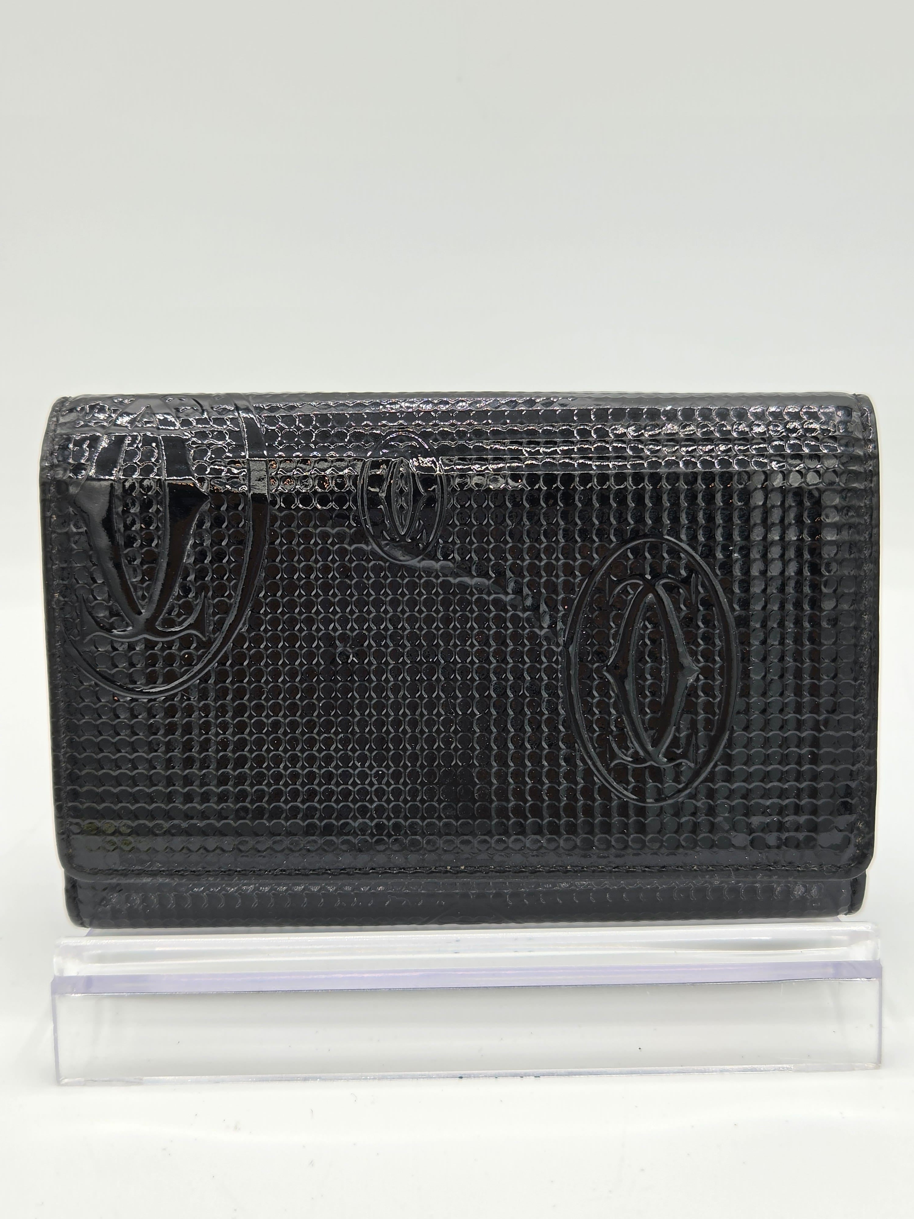 A black textured leather wallet with an embossed fish logo, shown next to a clear plastic protective sleeve on a white background.
