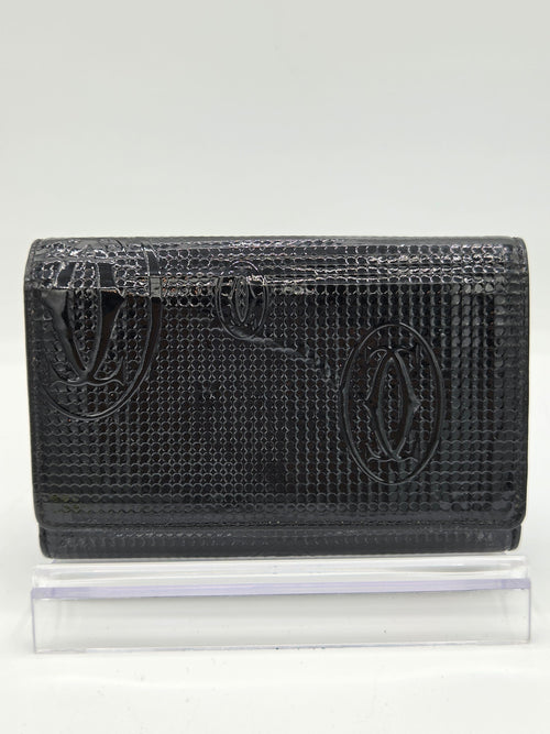 A black textured leather wallet with an embossed fish logo, shown next to a clear plastic protective sleeve on a white background.