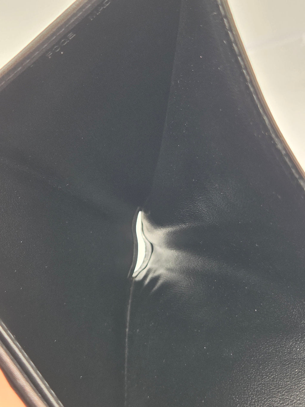 Close-up of a black leather or faux-leather product corner with a small silver metal accent visible at the center.