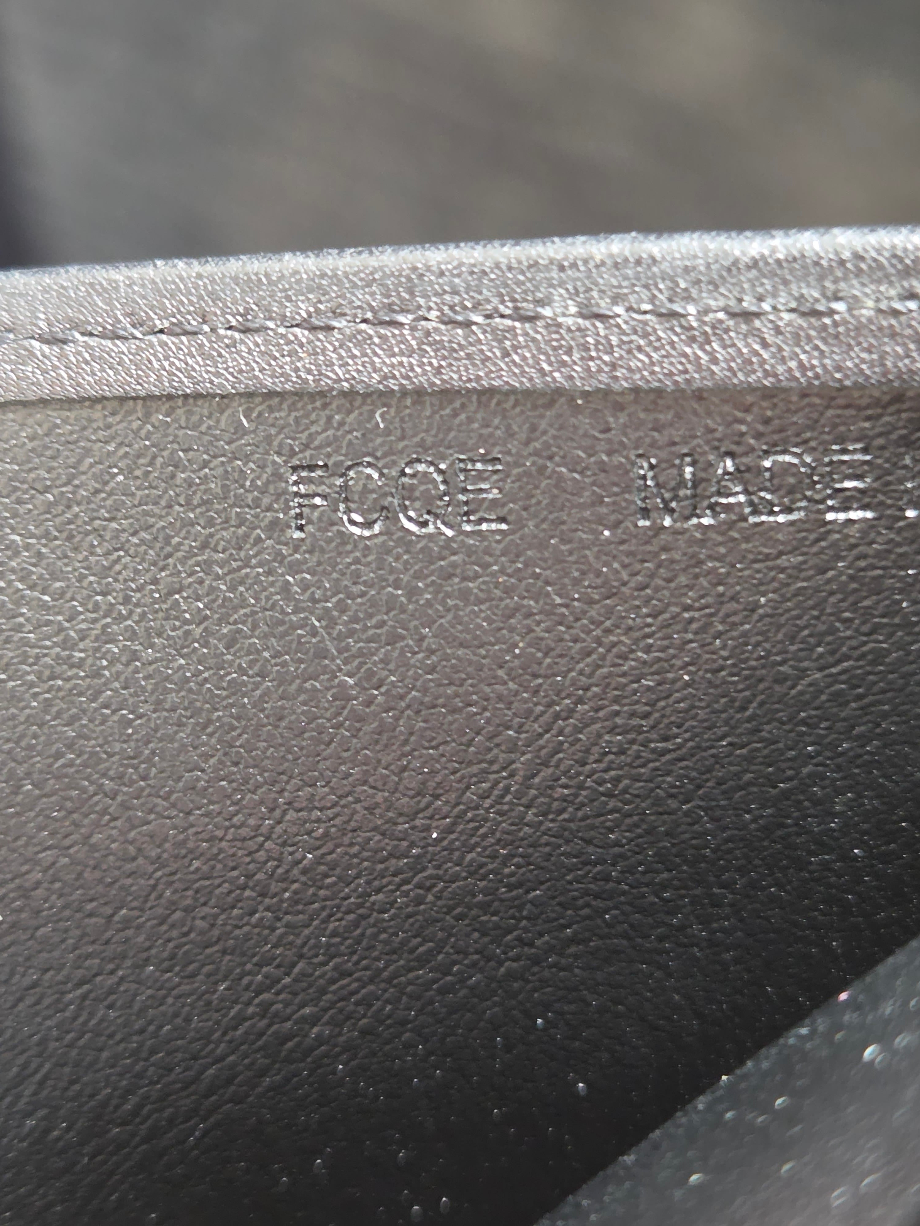 Close-up of a black pebbled leather or faux-leather material with a stitched edge and embossed vertical text reading 'FOGE MADE'.
