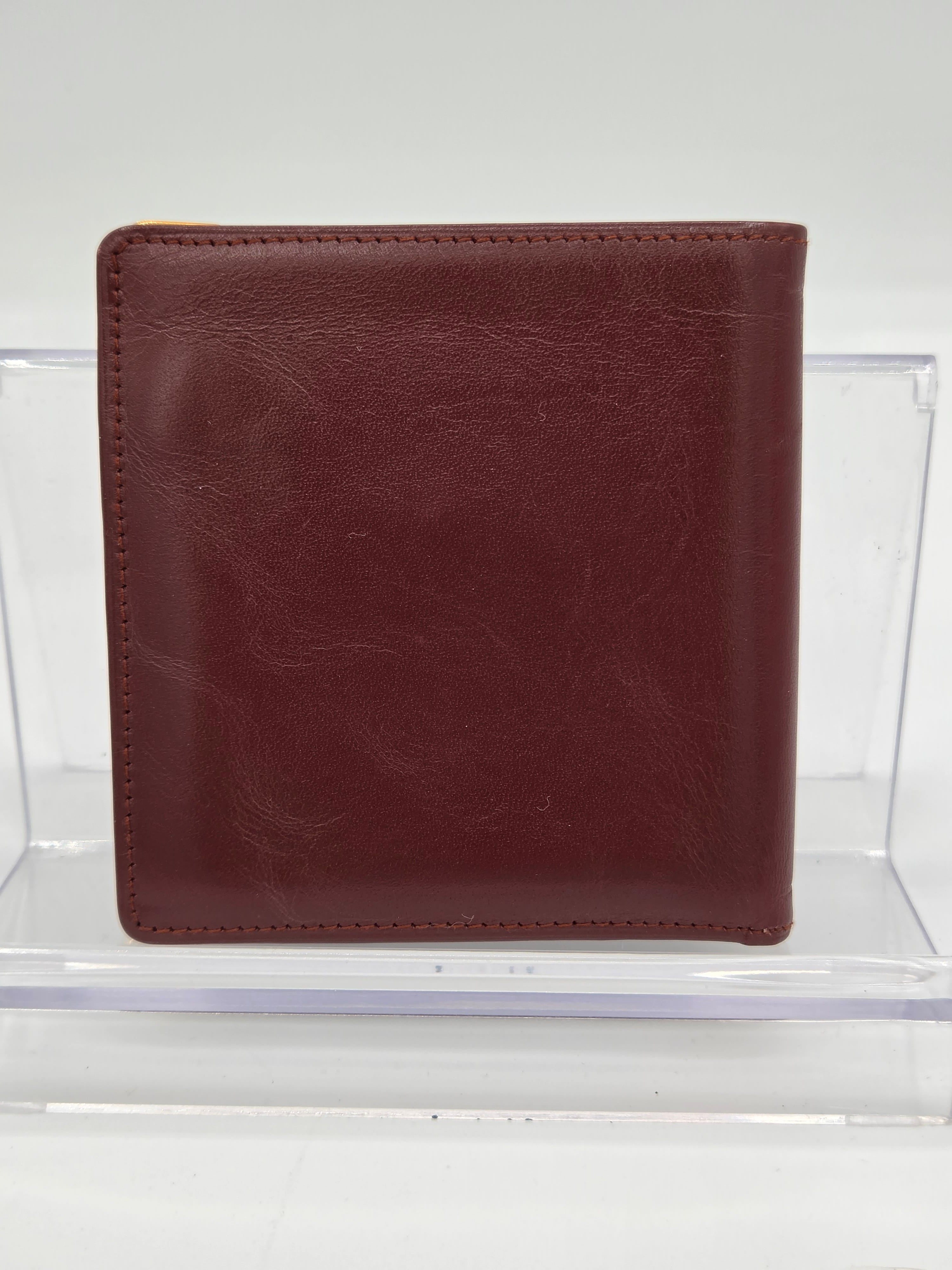 A dark brown leather bifold wallet displayed inside a clear acrylic block against a white background.