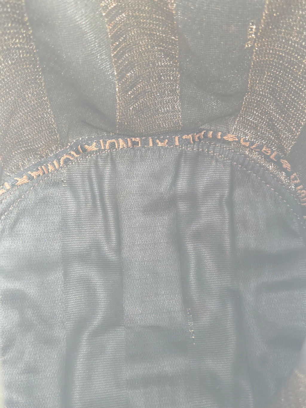 Close-up of a black mesh or tulle fabric accessory with a gathered elasticized edge and tonal stitching.