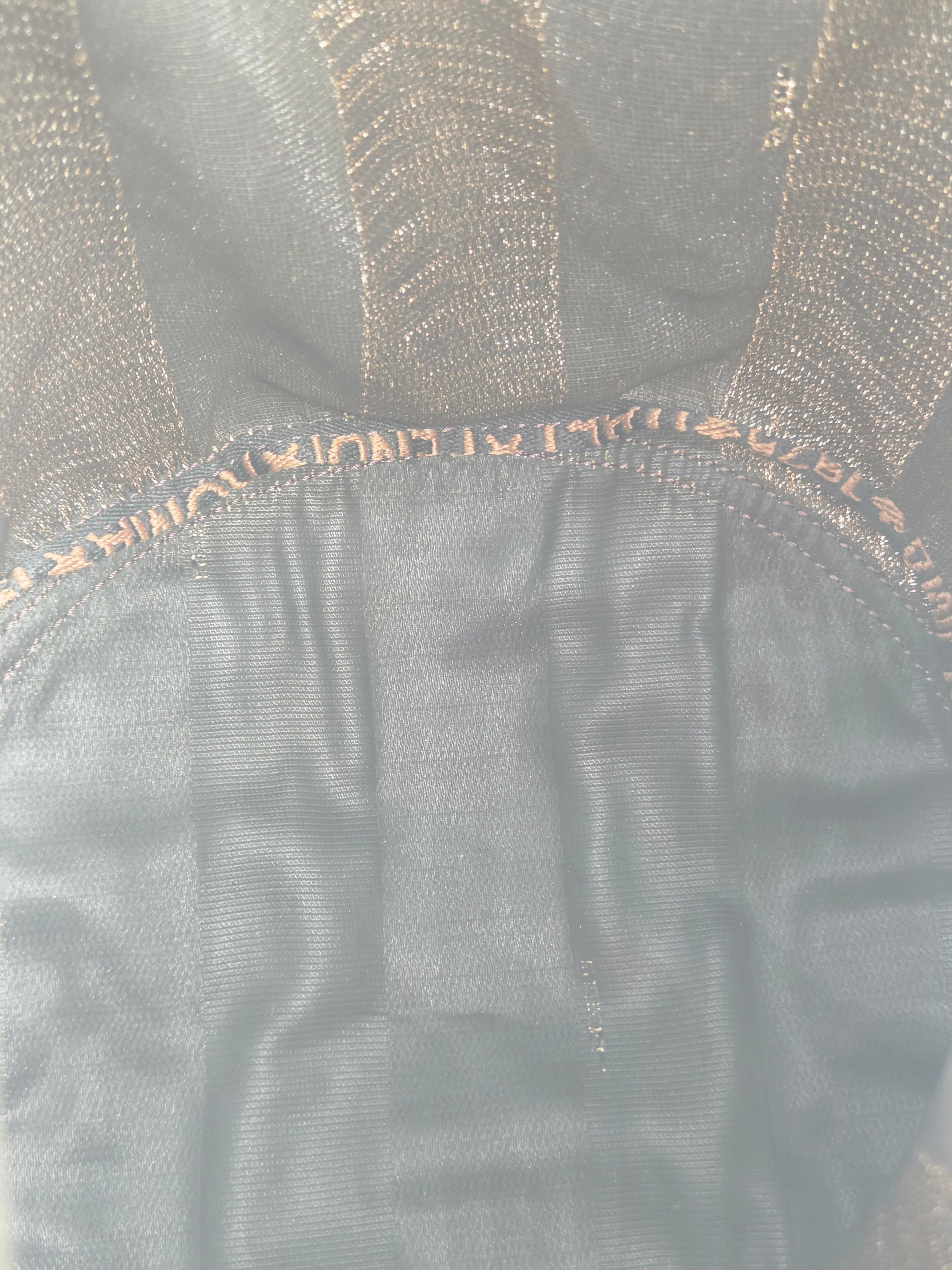 Close-up of a black mesh or tulle fabric accessory with a gathered elasticized edge and tonal stitching.