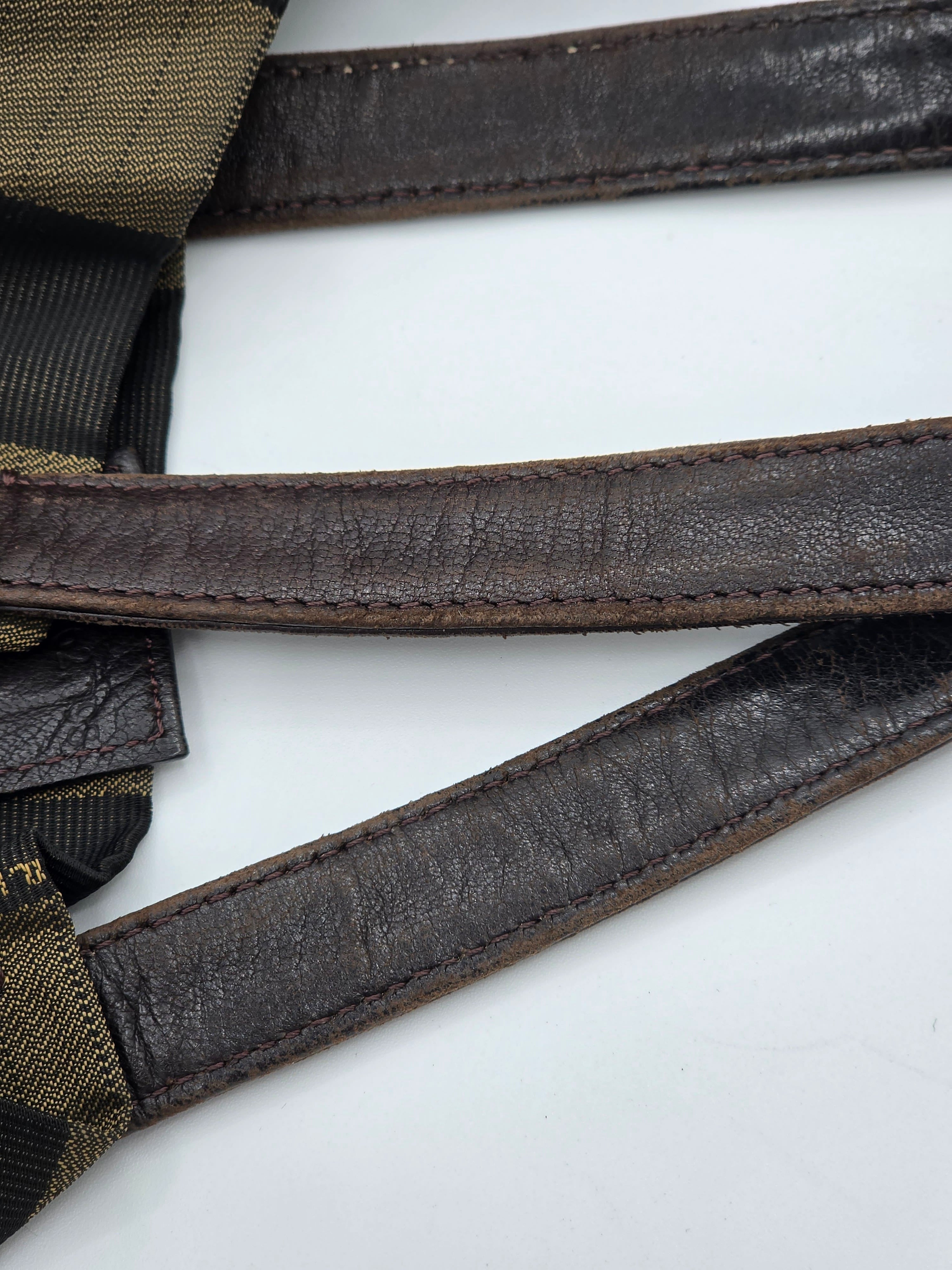 Close-up of dark brown leather straps with visible stitching and a tan-and-black woven fabric section on a white background.