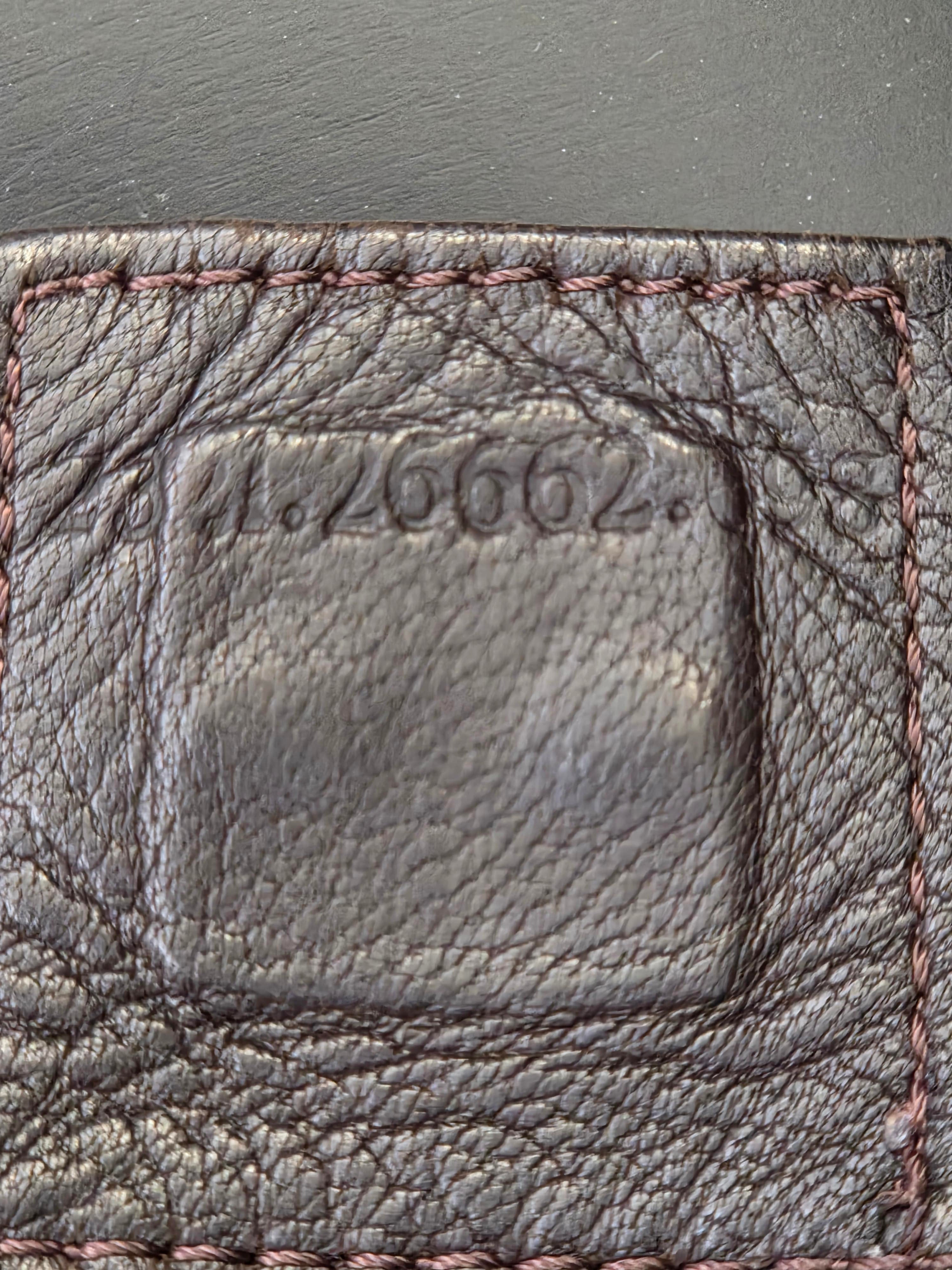 Close-up of a dark brown textured leather item, showing a stitched border and embossed vertical numbering.