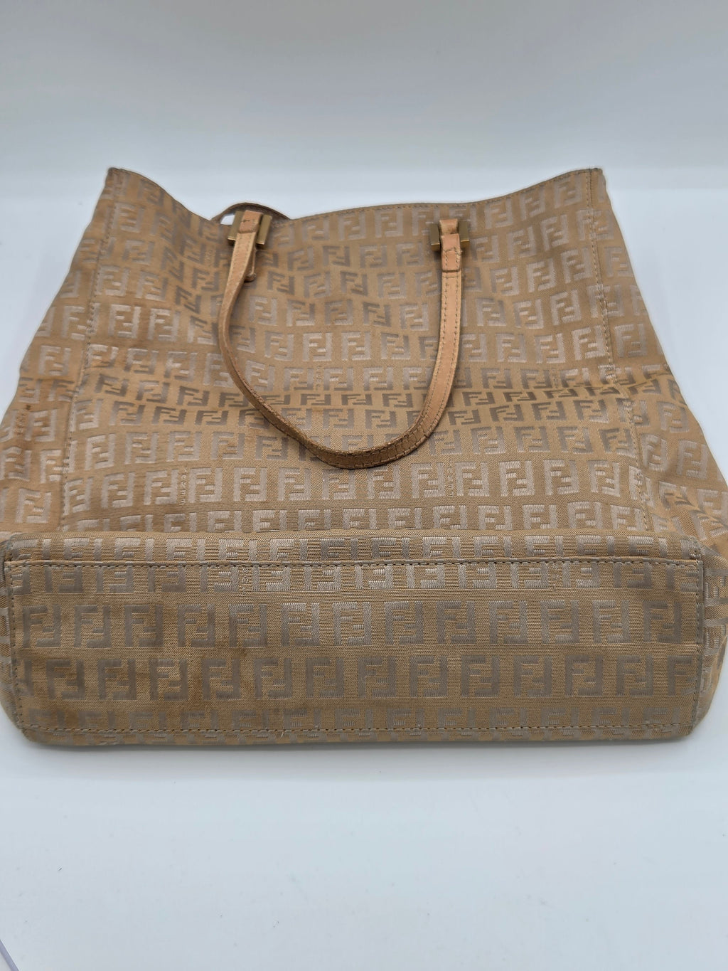 A vintage Fendi tote bag in beige Zucca monogram canvas with tan leather shoulder straps, photographed on a neutral light gray background.