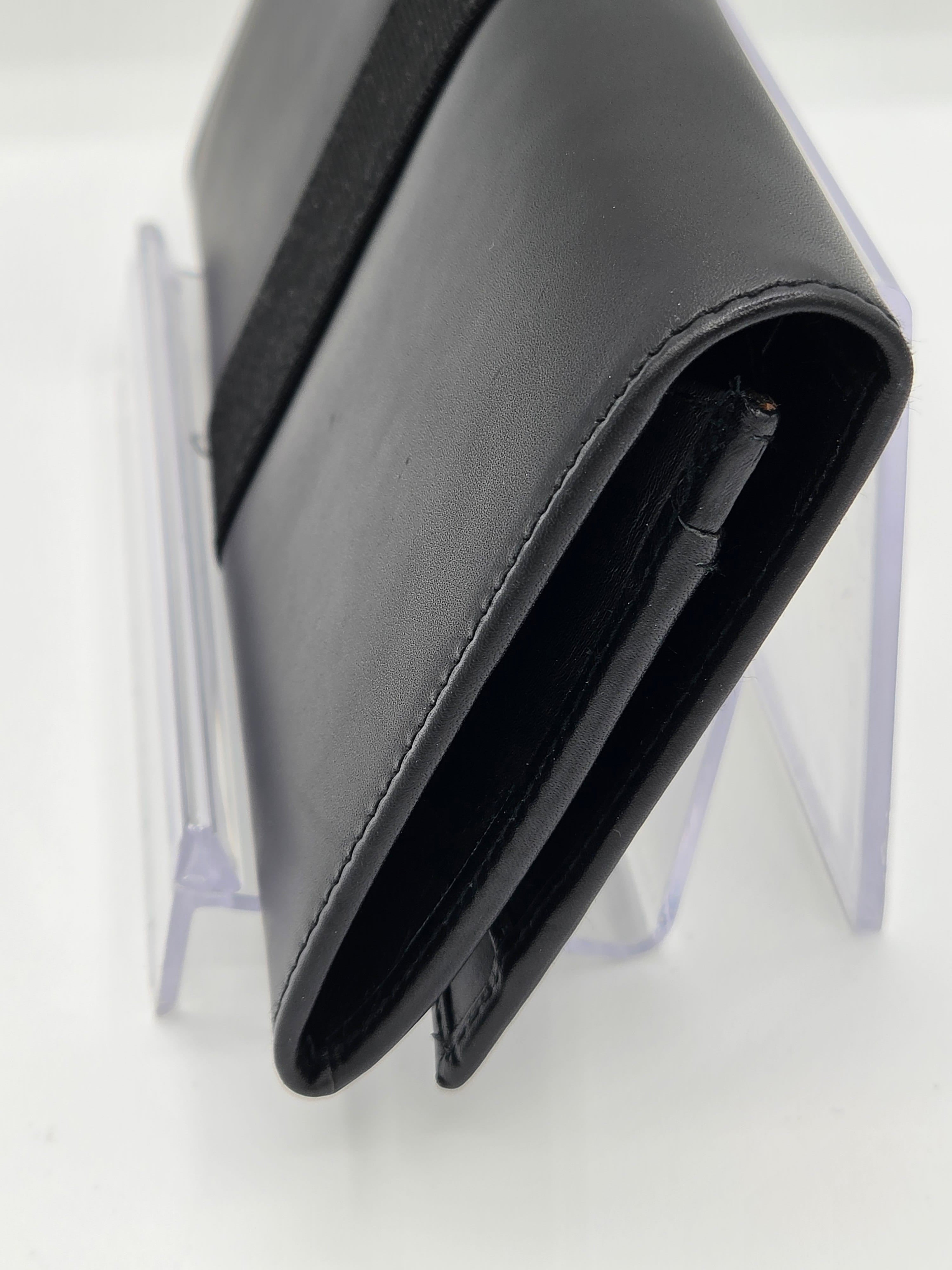 A close-up of a black leather wallet or card holder standing on a clear acrylic display stand against a white background.