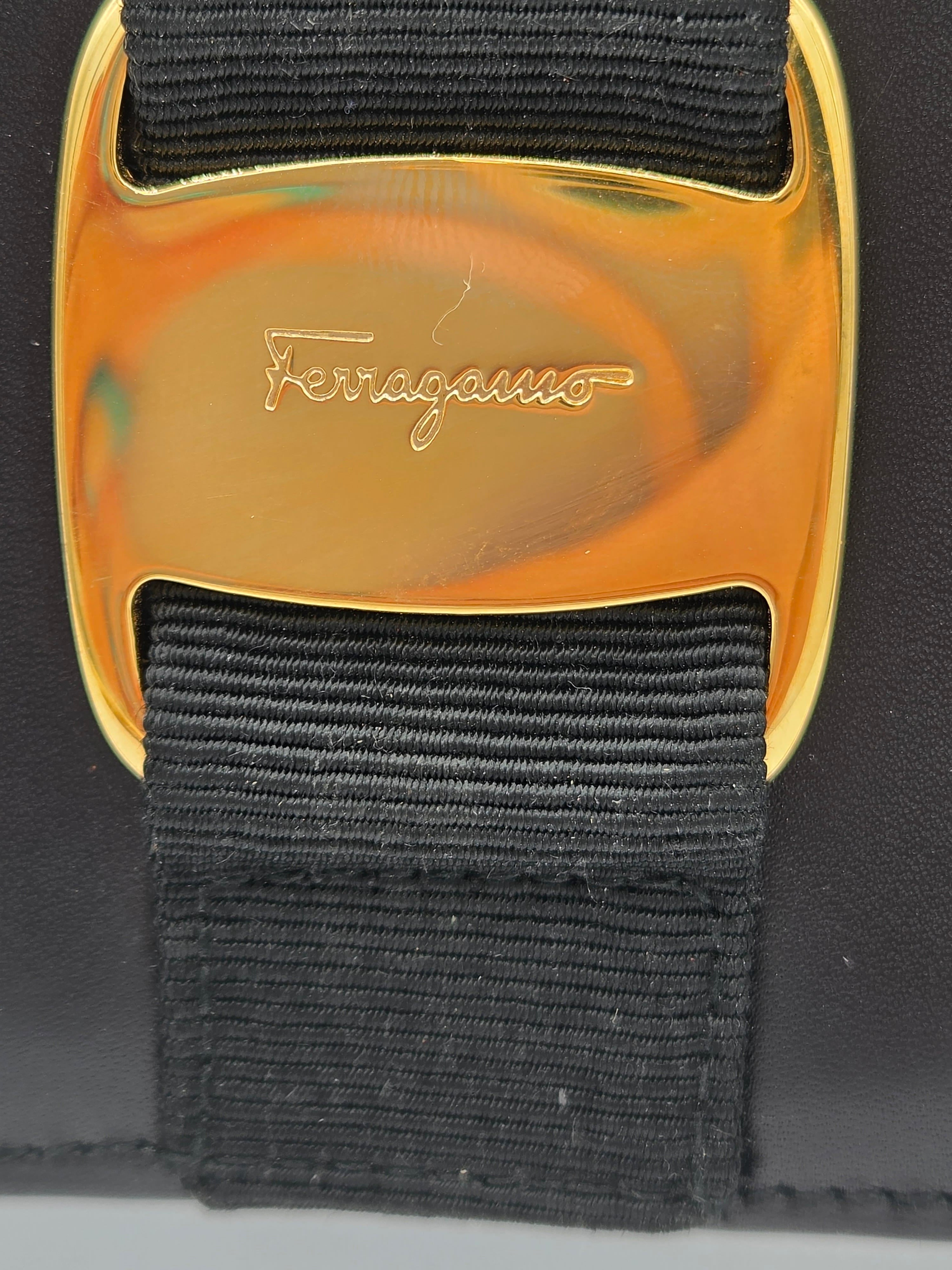 Close-up of a black woven strap with a polished gold-tone buckle engraved with the Ferragamo logo.