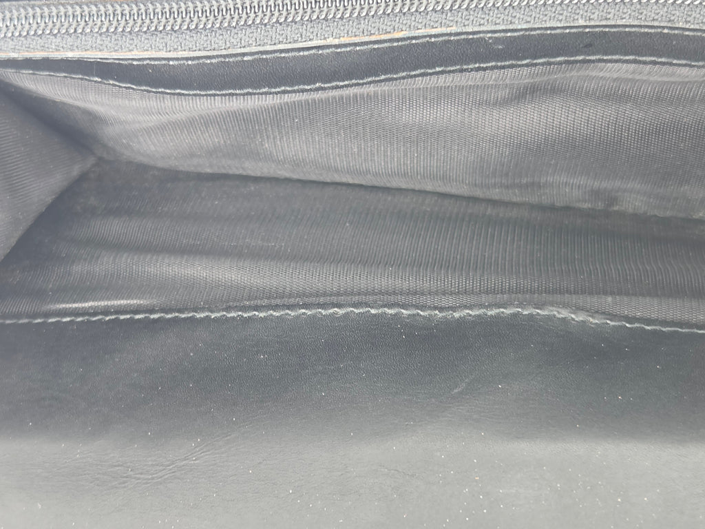 Close-up of the interior of a dark gray or black leather and fabric bag, showing stitched compartments and a zipper.