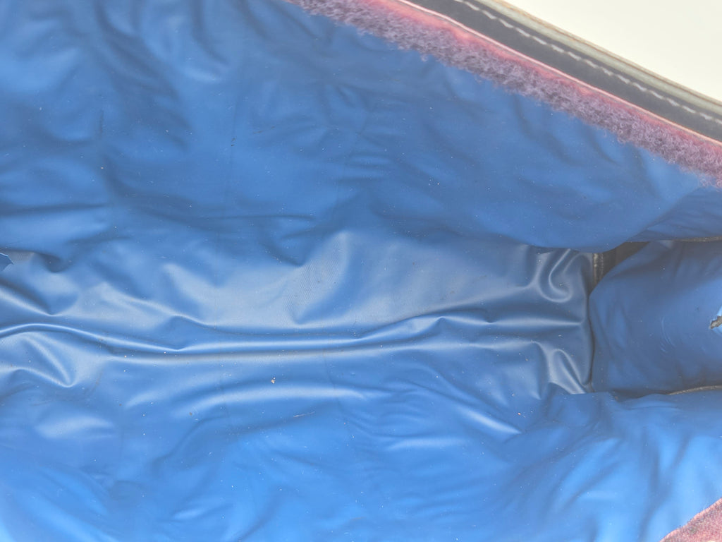 Close-up of a blue vinyl or plastic cover with a textured, slightly wrinkled surface and a dark reddish-brown fuzzy trim along the edge.