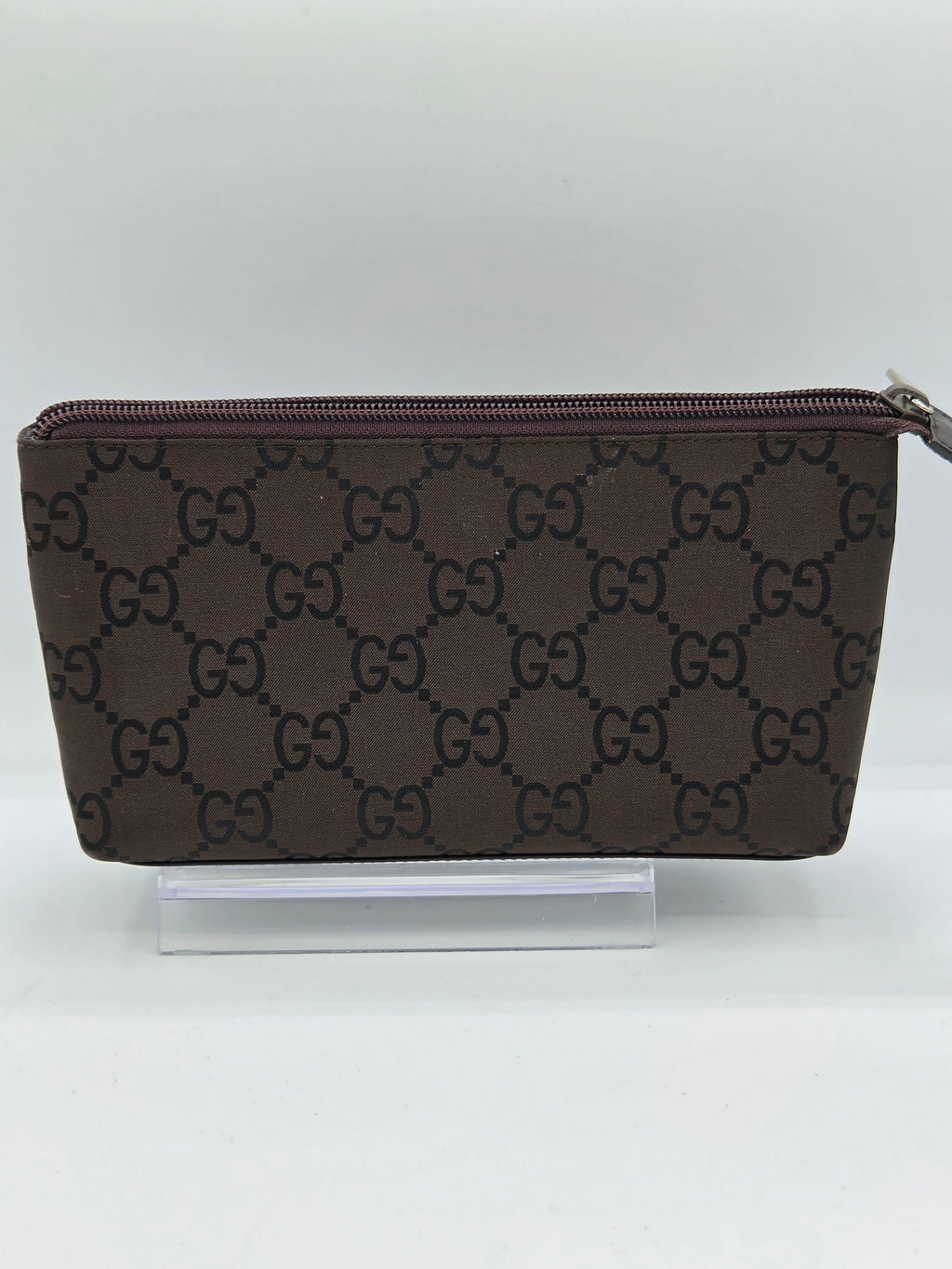 A brown monogram zip-around pouch with a repeating interlocking G pattern, shown standing upright against a plain white background.
