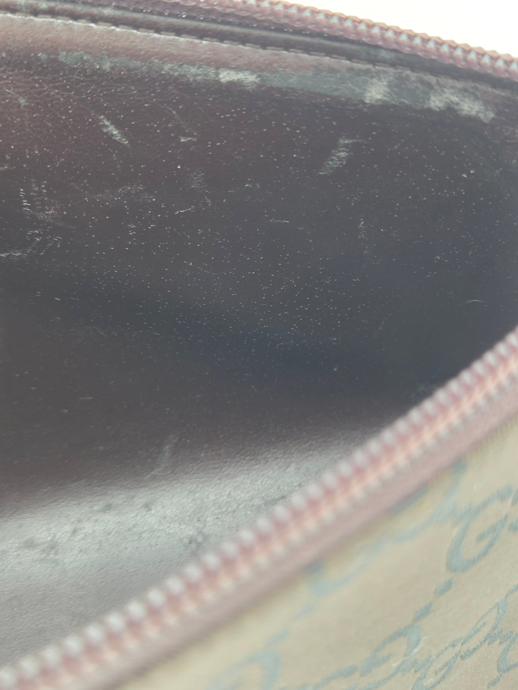 Close-up of an open zippered pouch showing a dark brown textured interior, a pink zipper, and a beige patterned exterior.