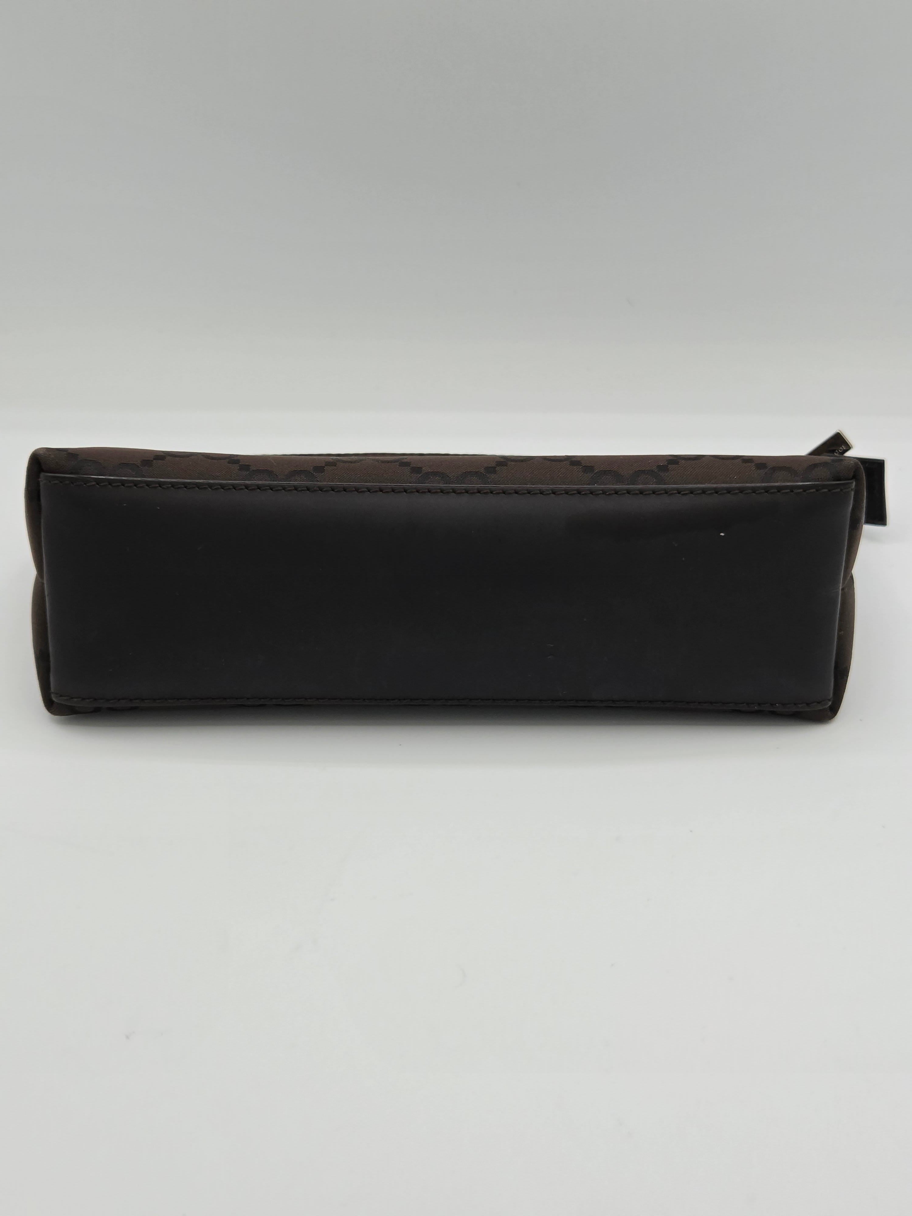 A dark brown leather pouch with a subtle monogram pattern, shown vertically against a plain light gray background.