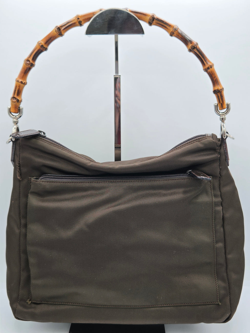 A dark brown nylon shoulder bag with a distinctive curved bamboo handle, displayed on a white background.