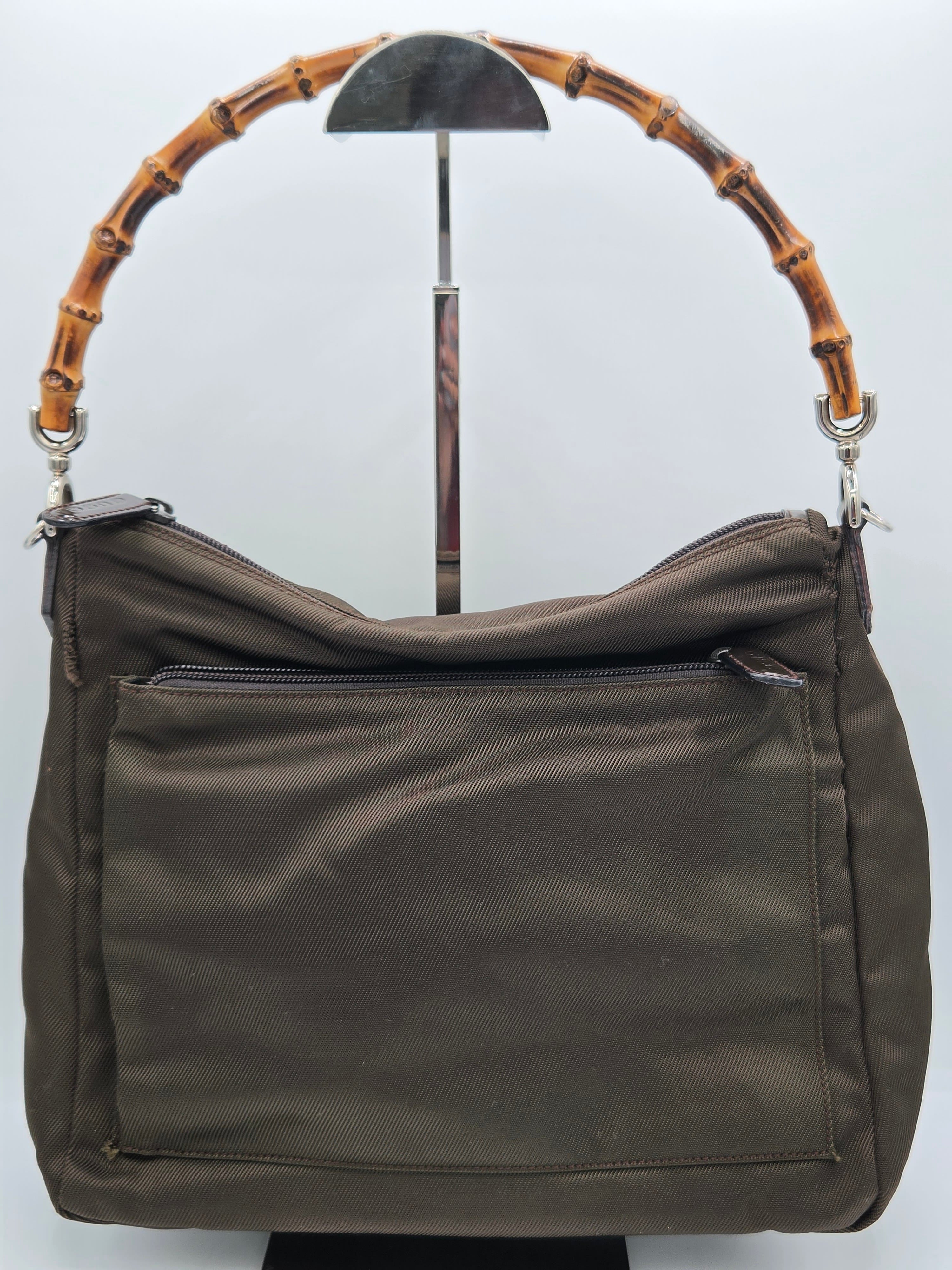 A dark brown nylon shoulder bag with a distinctive curved bamboo handle, displayed on a white background.