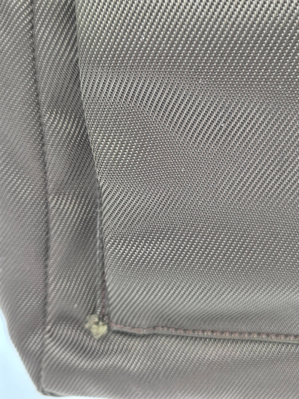 Close-up of a gray textured fabric surface with diagonal woven pattern and a visible seam.