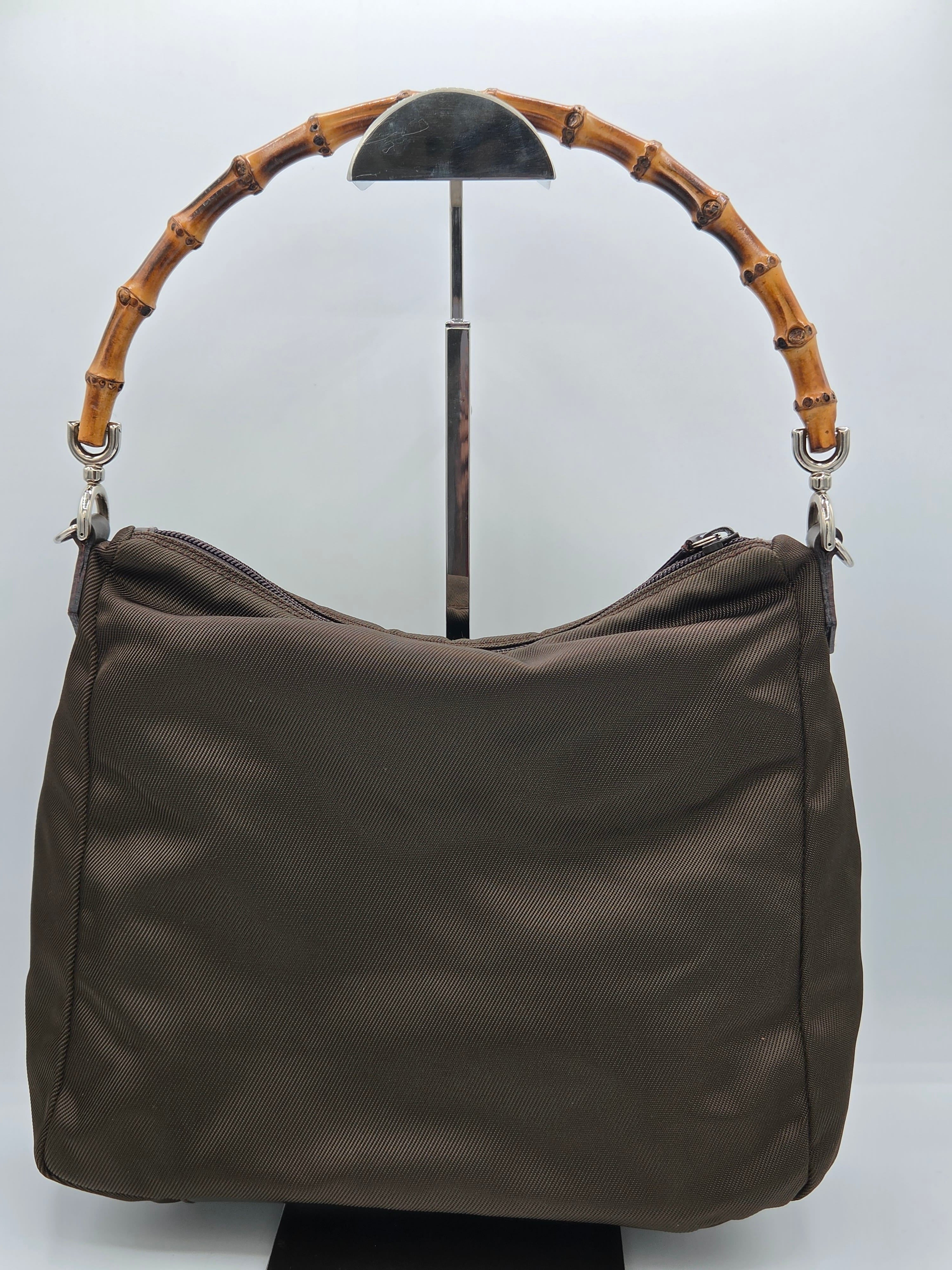 A dark brown shoulder bag with a distinctive curved bamboo handle, displayed on a white background.