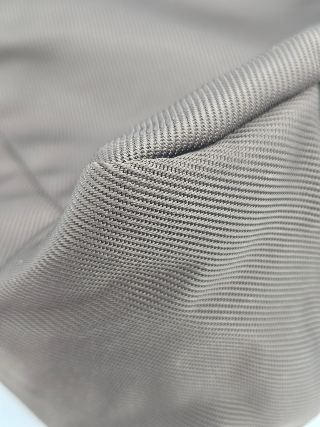 Close-up of a light gray ribbed fabric texture with a folded corner showing the woven material detail.