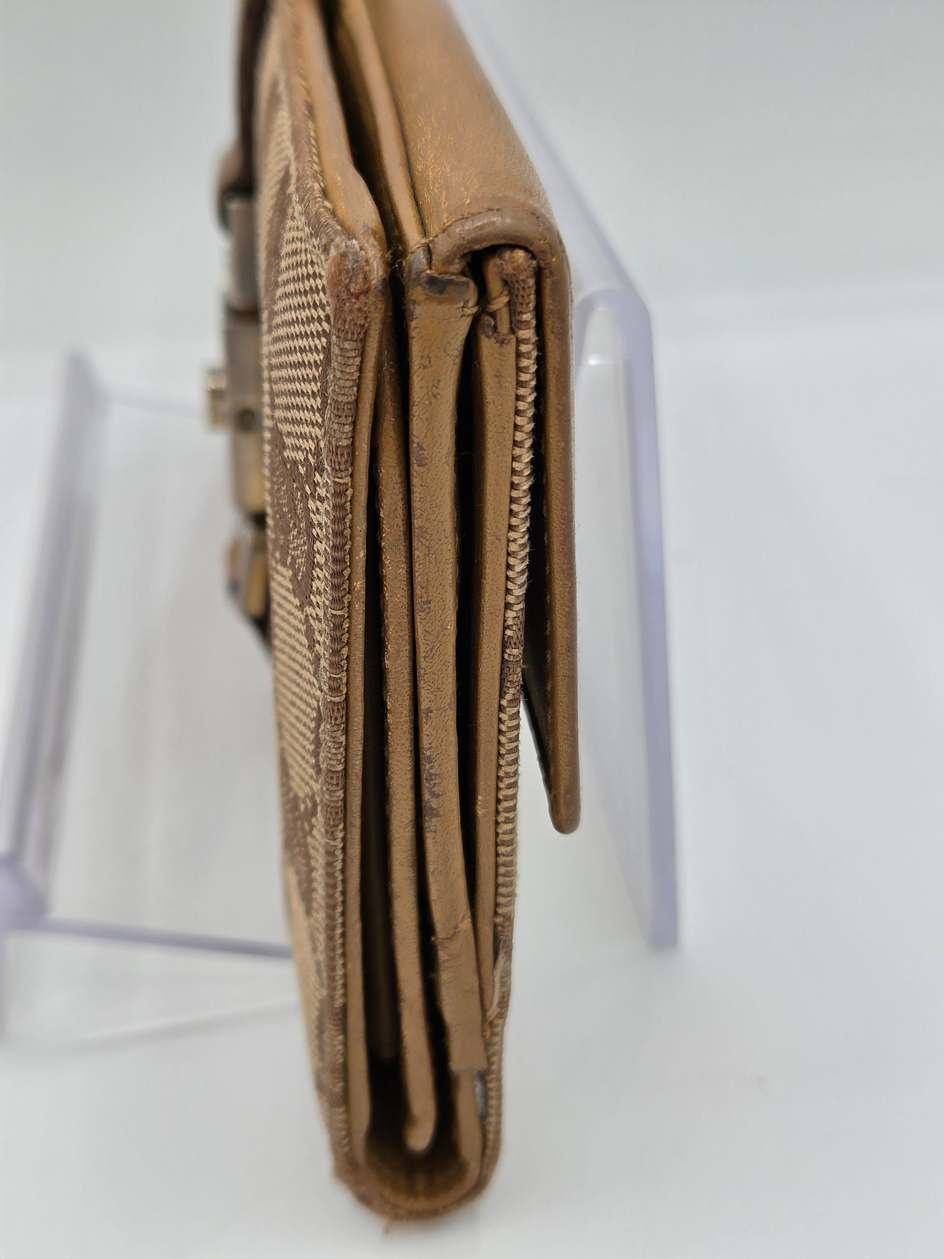 A close-up side view of a tan leather wallet with a textured woven pattern, resting on a clear acrylic display stand against a white background.