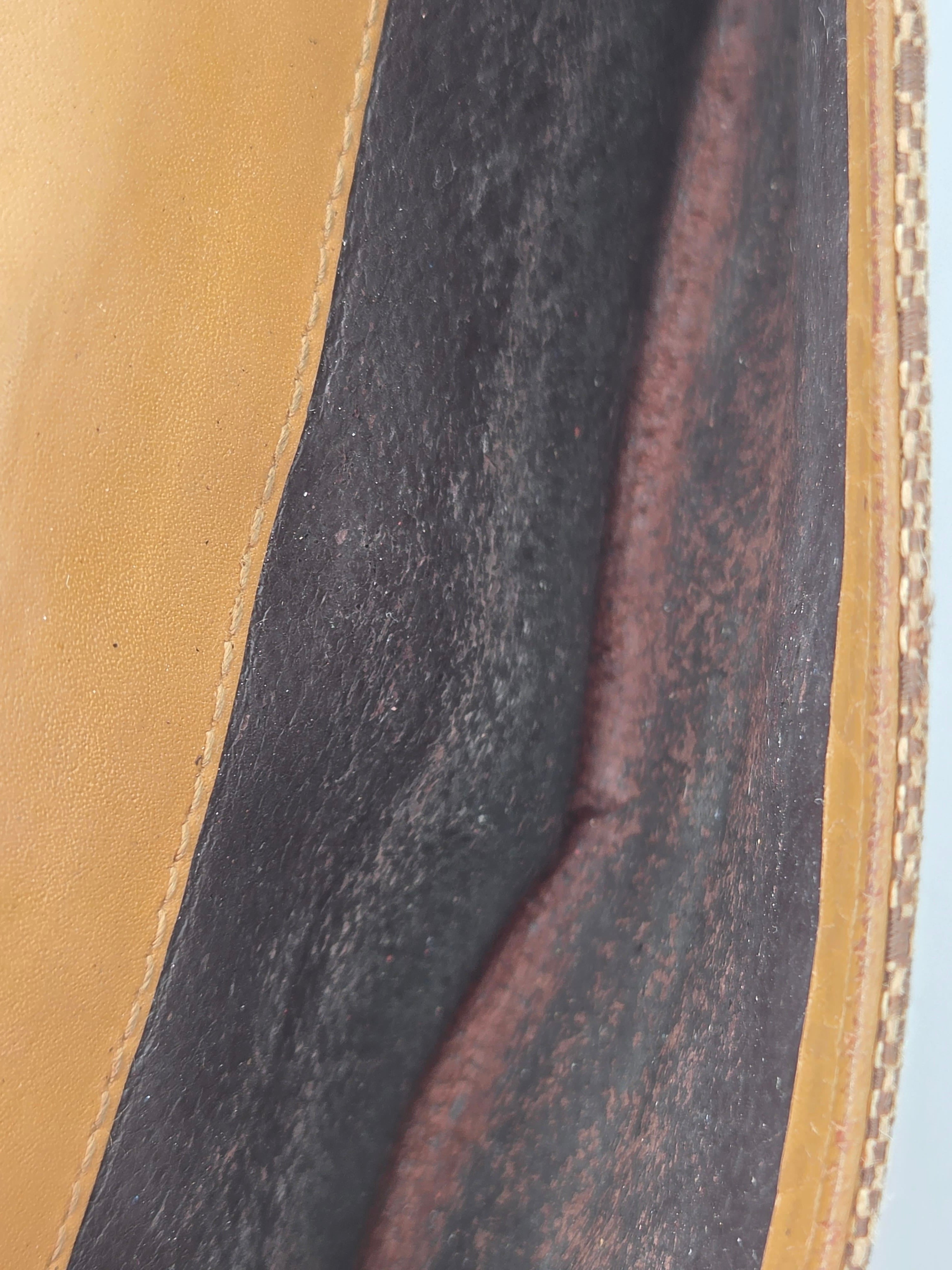 Close-up detail of a leather bag showing a dark charcoal textured interior panel bordered by tan leather trim.