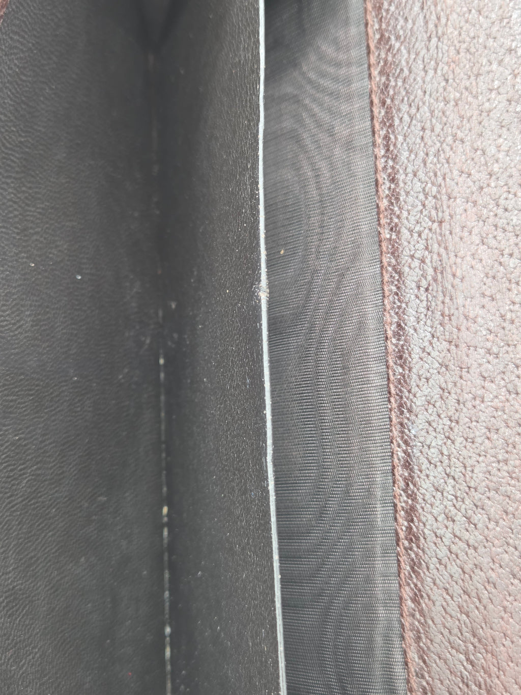 Close-up detail of a dark gray textured material with a stitched seam and a lighter gray horizontal divider.