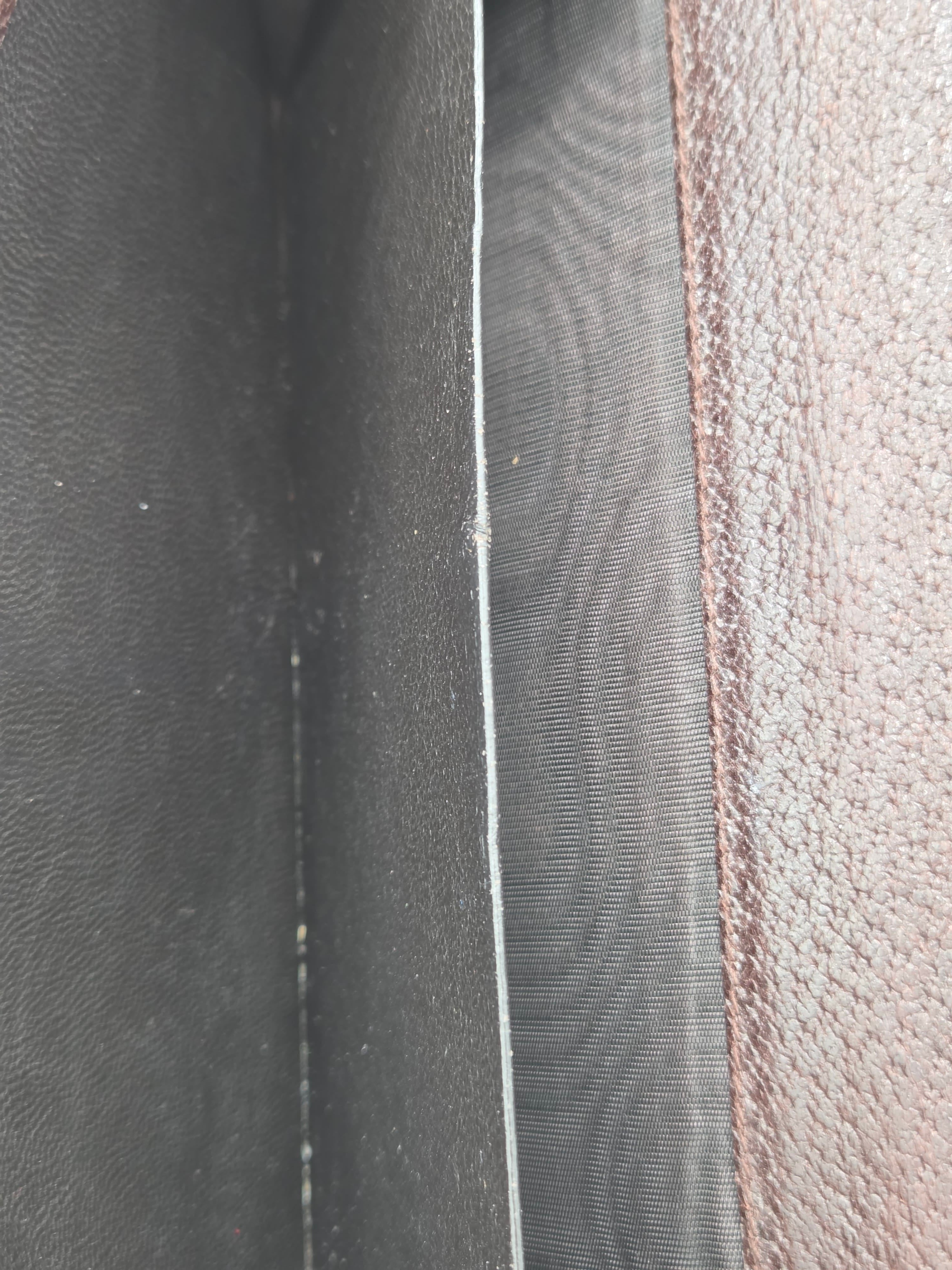 Close-up detail of a dark gray textured material with a stitched seam and a lighter gray horizontal divider.