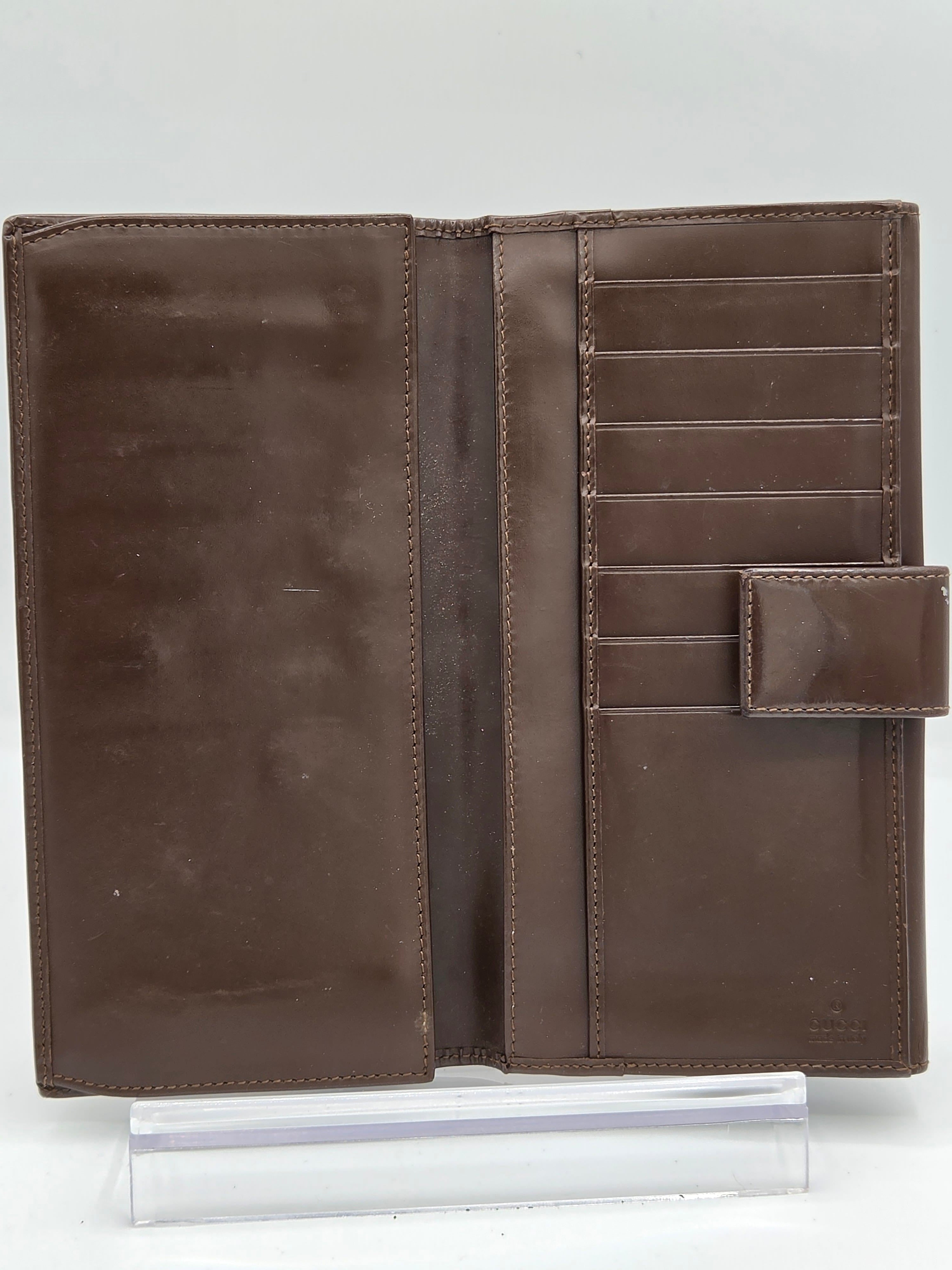 A brown leather wallet shown open, displaying multiple card slots, a central slip pocket, and a top strap closure, photographed on a plain white background.