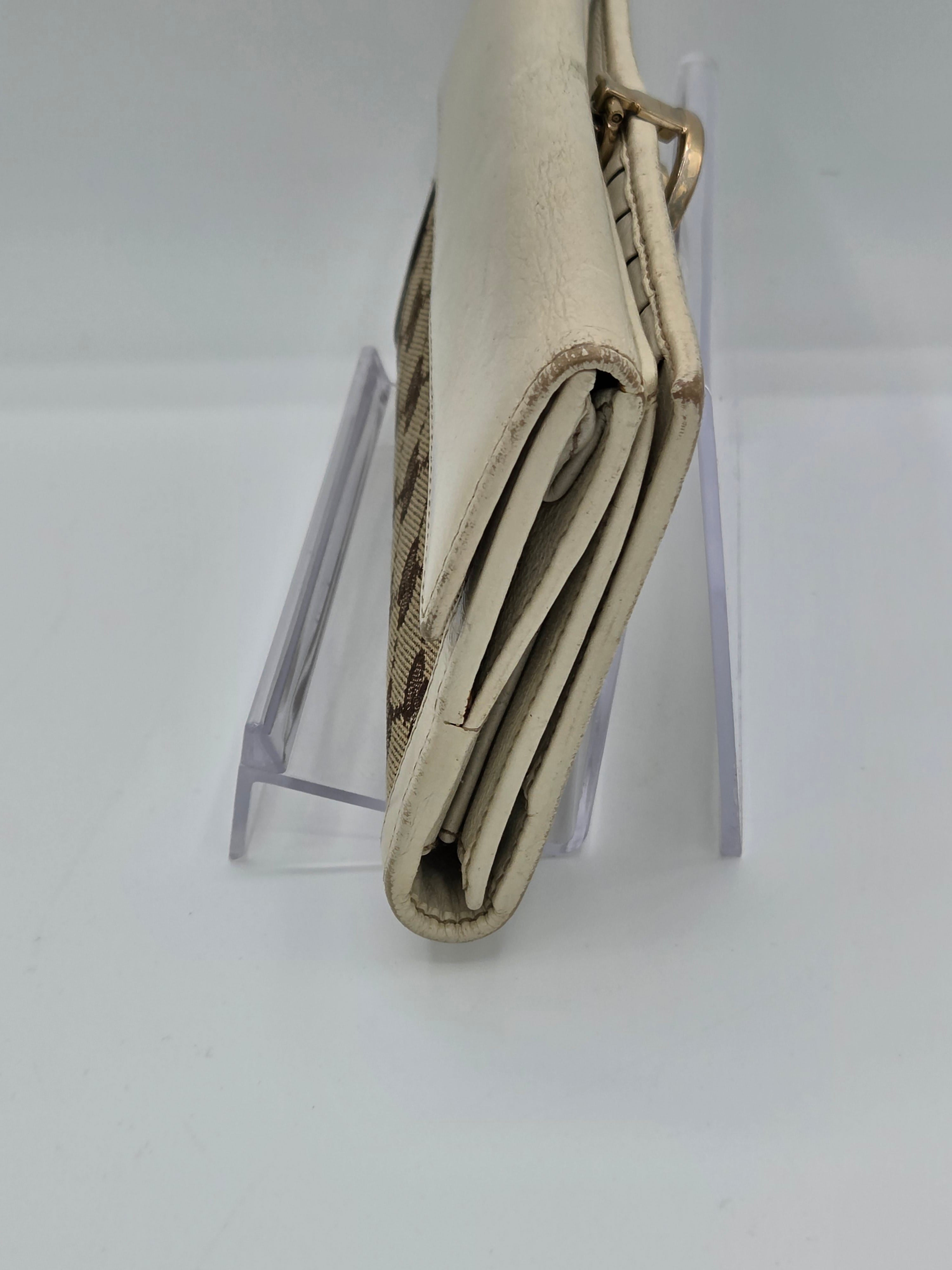 A close-up of a folded beige leather wallet or card holder with a woven patterned interior, displayed on a clear acrylic stand against a white background.