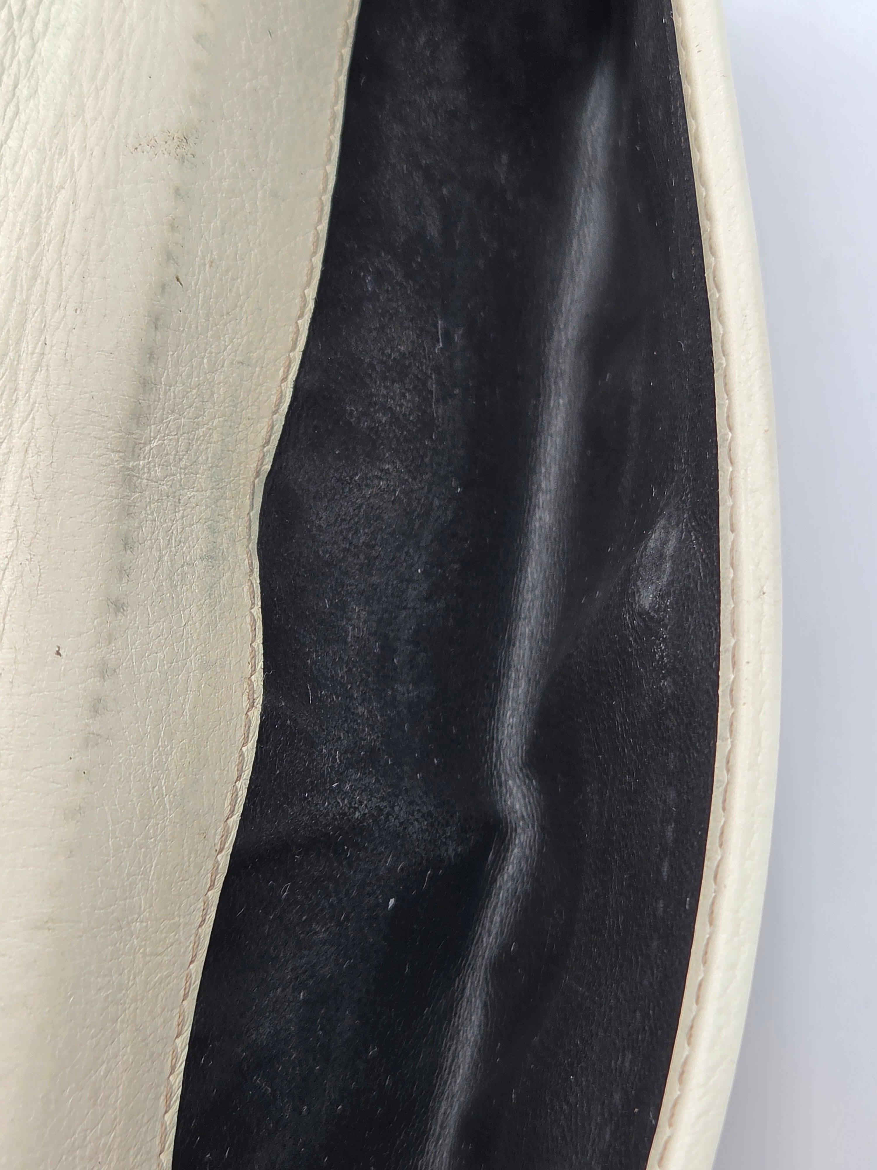 Close-up of a cream-colored leather bag showing the interior black lining and stitched edge.