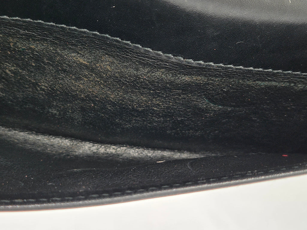 Close-up of a black leather interior or flap showing the grain texture and stitching detail.