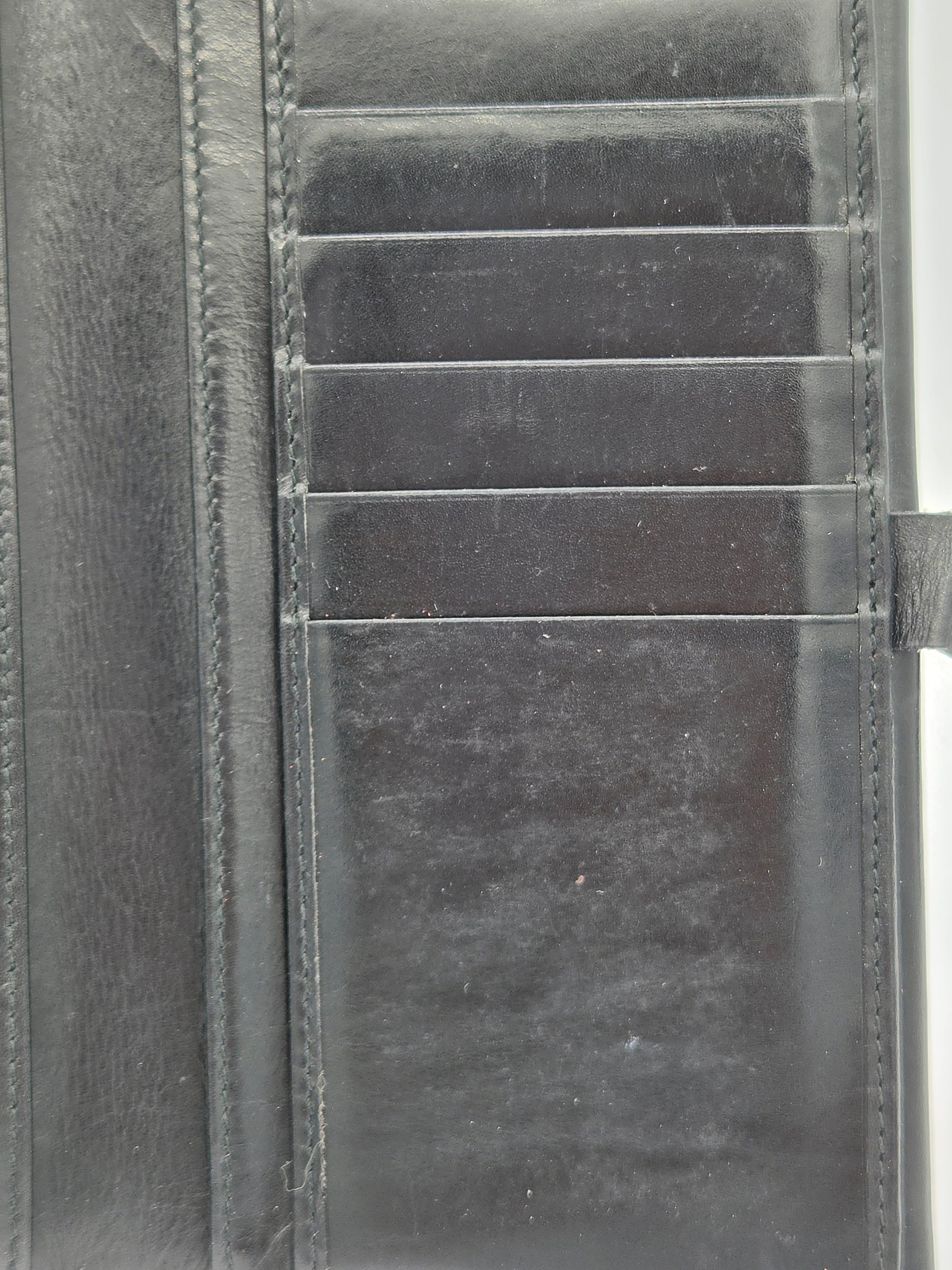 Close-up of a dark gray leather wallet showing card slots, stitching, and a textured leather surface.