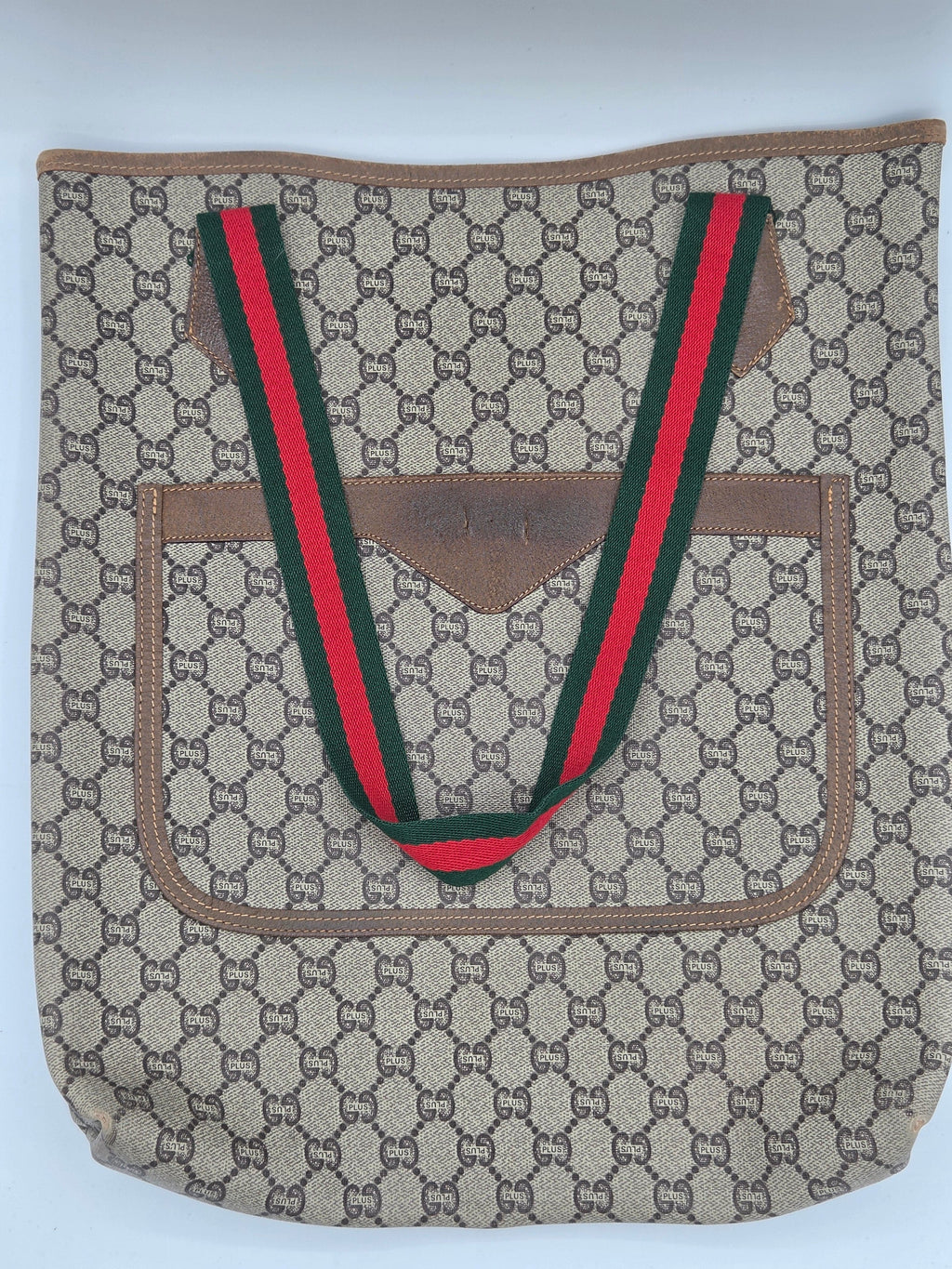 A vintage Gucci shoulder bag in the classic GG Supreme canvas, featuring a brown leather trim and signature green and red web stripe handles.