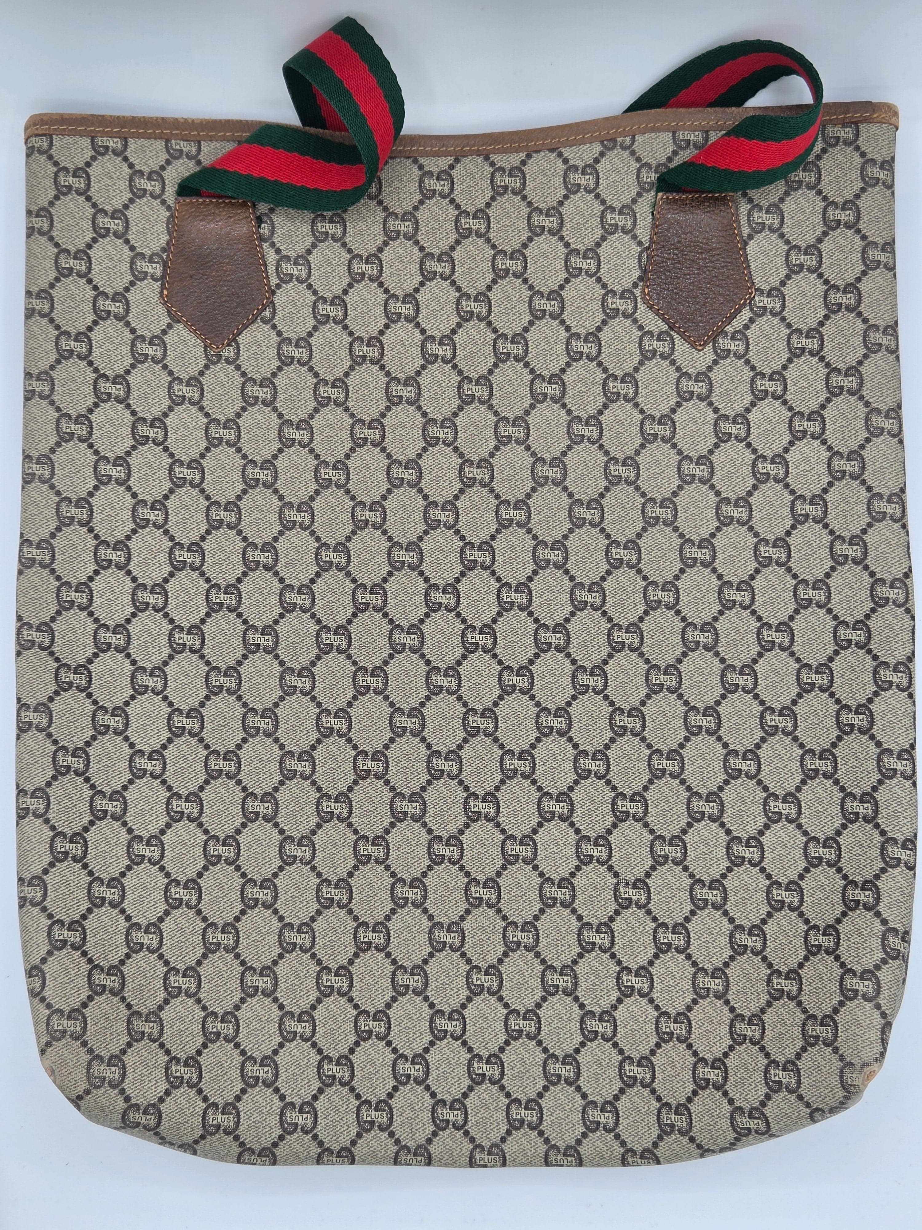 A Gucci canvas tote bag featuring the signature GG monogram pattern in beige and brown, with green and red web stripe accents on the handles and brown leather trim.