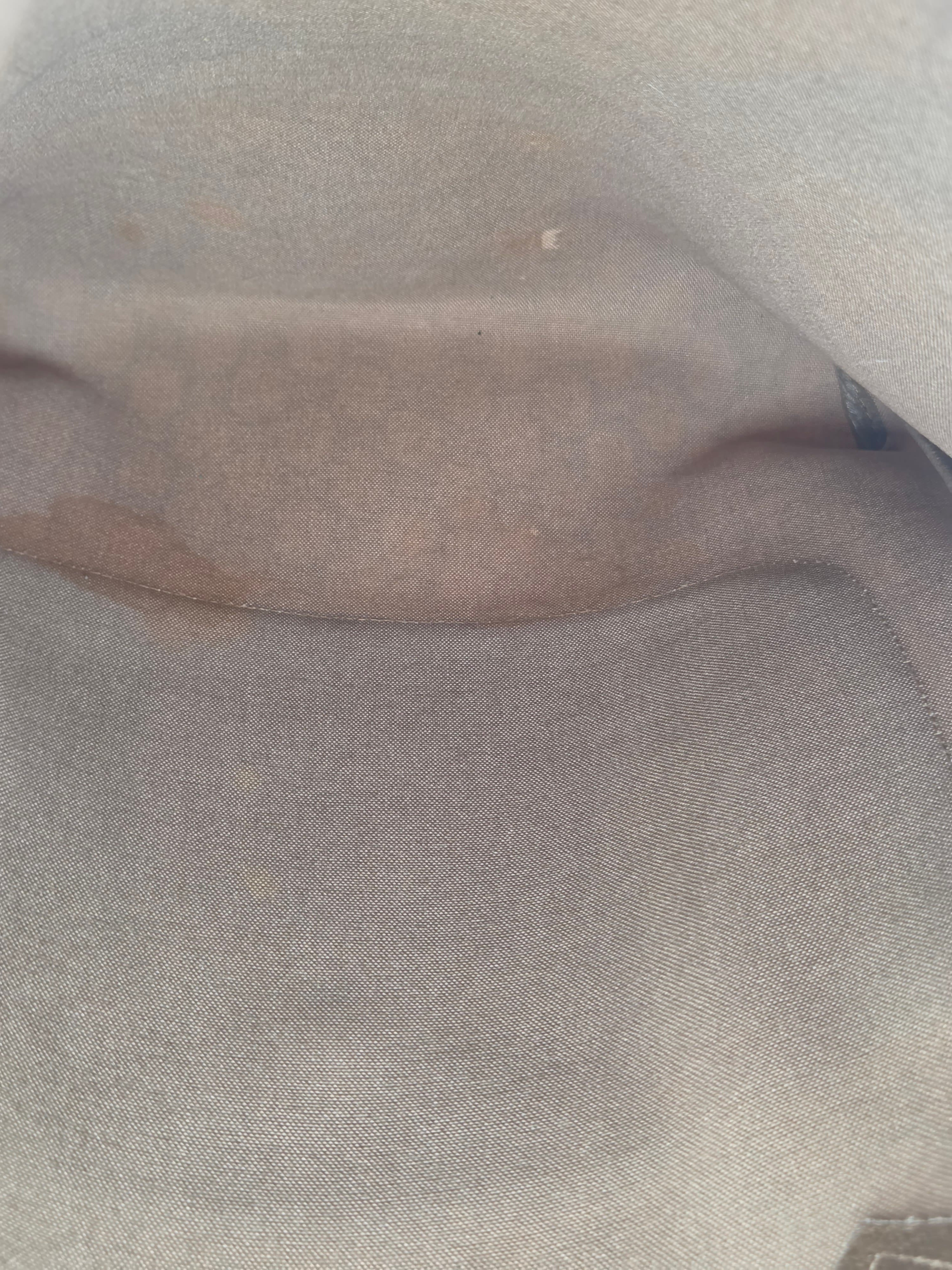A close-up view of a light gray fabric surface with visible texture and folds.