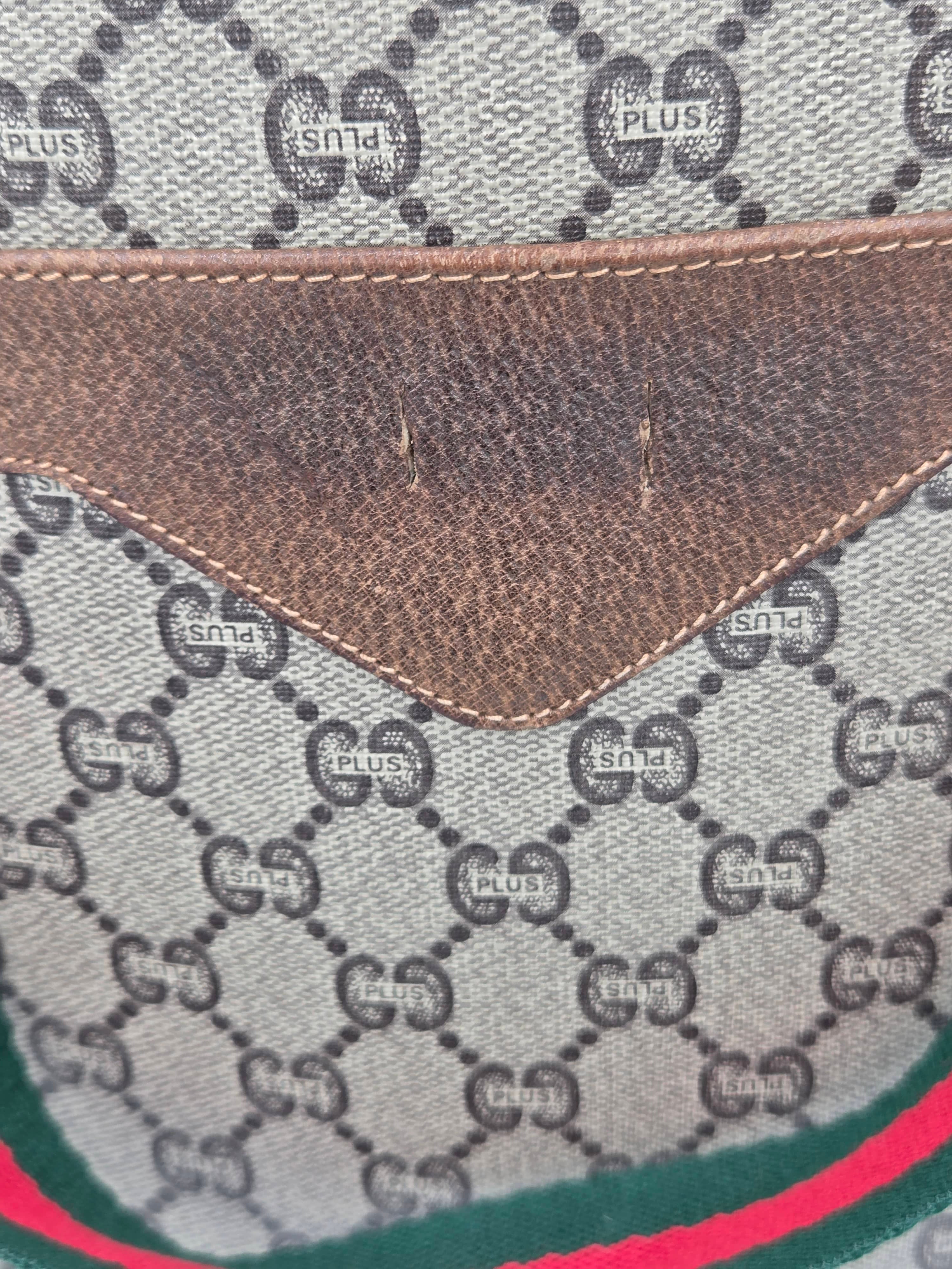 Close-up of a Gucci monogram canvas bag with a brown leather trim and green and red stripe detail.